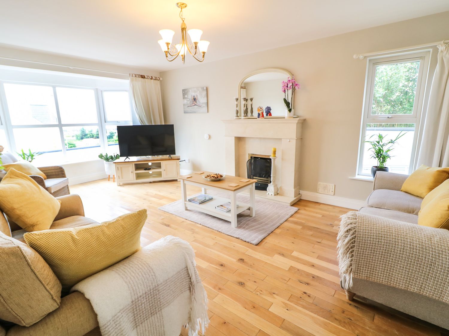 A living room with sofas, a coffee table, a television, a fireplace, and windows at 12 Hillview in Ludden near Buncrana
