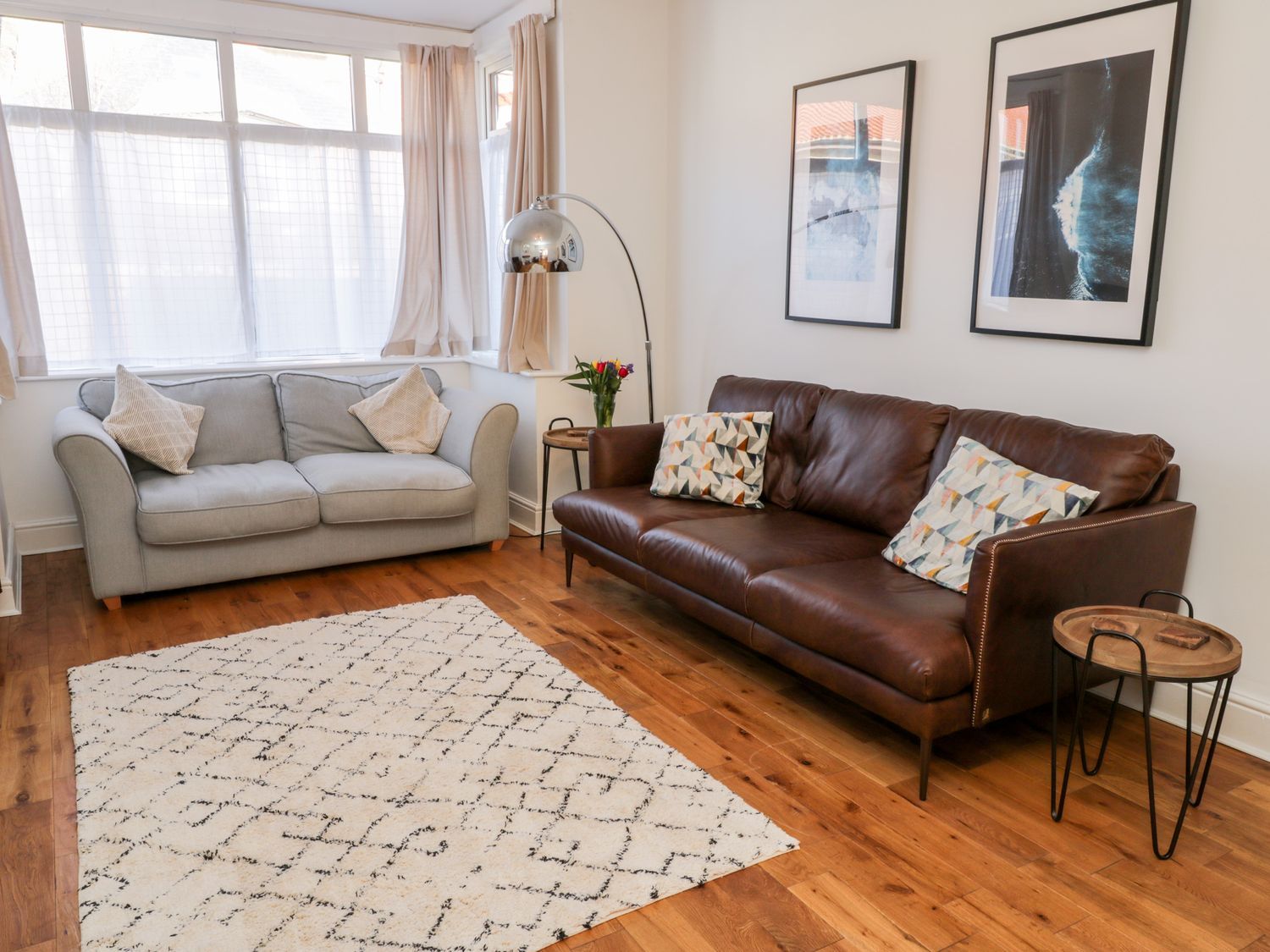 A living room with two sofas a floor lamp a wooden side table a rug and framed pictures on the wall at Fern House in Whitby