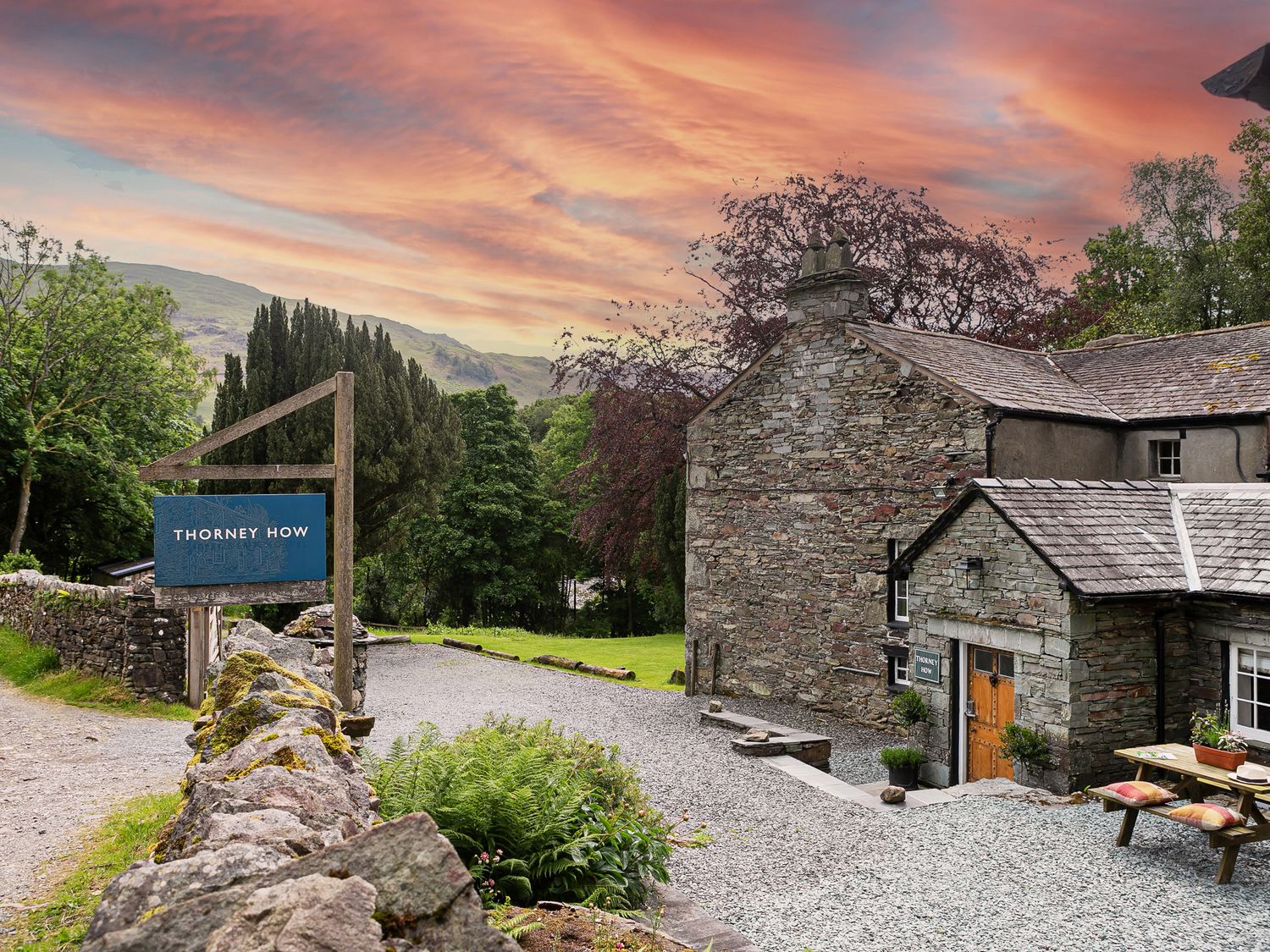 An outdoor stone building with a wooden door and a picnic table outside at Thorney How in Grasmere