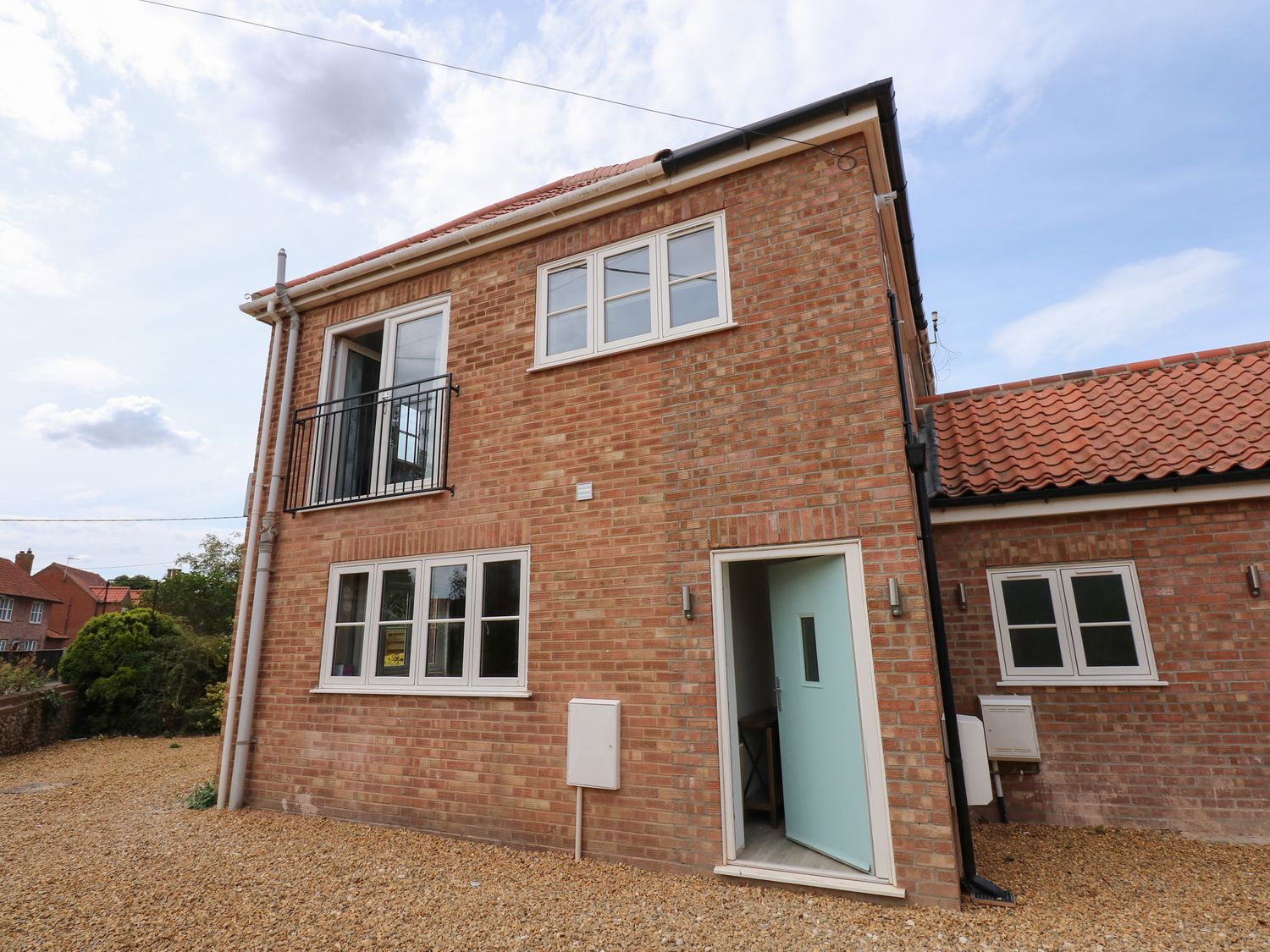 A brick exterior of a two-story house with multiple windows and an open door at Jolly Sailors Retreat - Wells next the Sea in Wells-Next-The-Sea