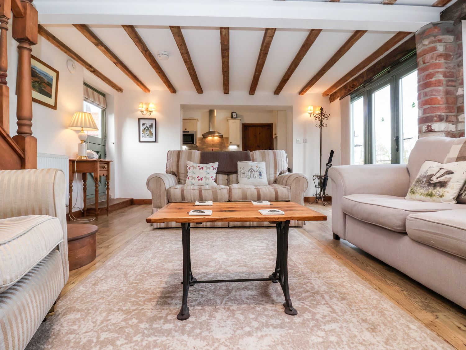 A living room with sofas a wooden coffee table and exposed ceiling beams at The Cart House in Skipsea