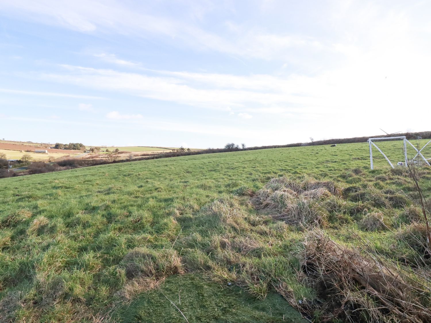 A grassy field with a small soccer goal and rolling countryside in the background at Penpethy Farm Tintagel