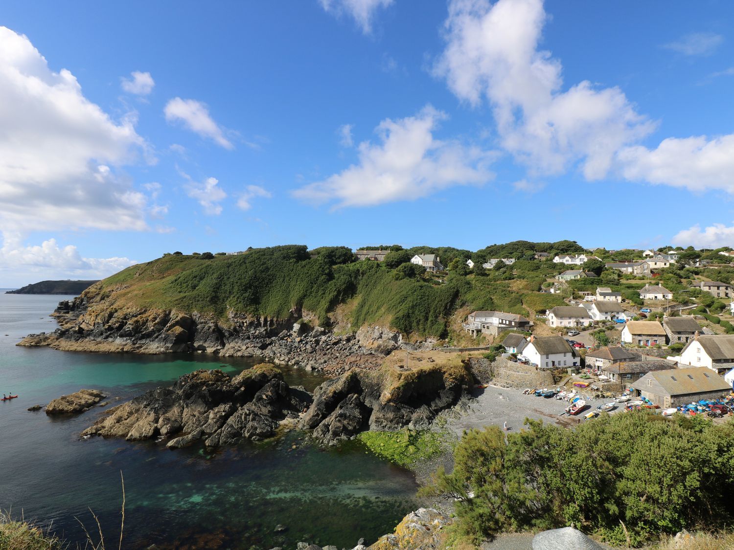 A coastal village with houses on a hillside overlooking rocky shore and sea at Tregonning Lodge Ashton near Rosudgeon