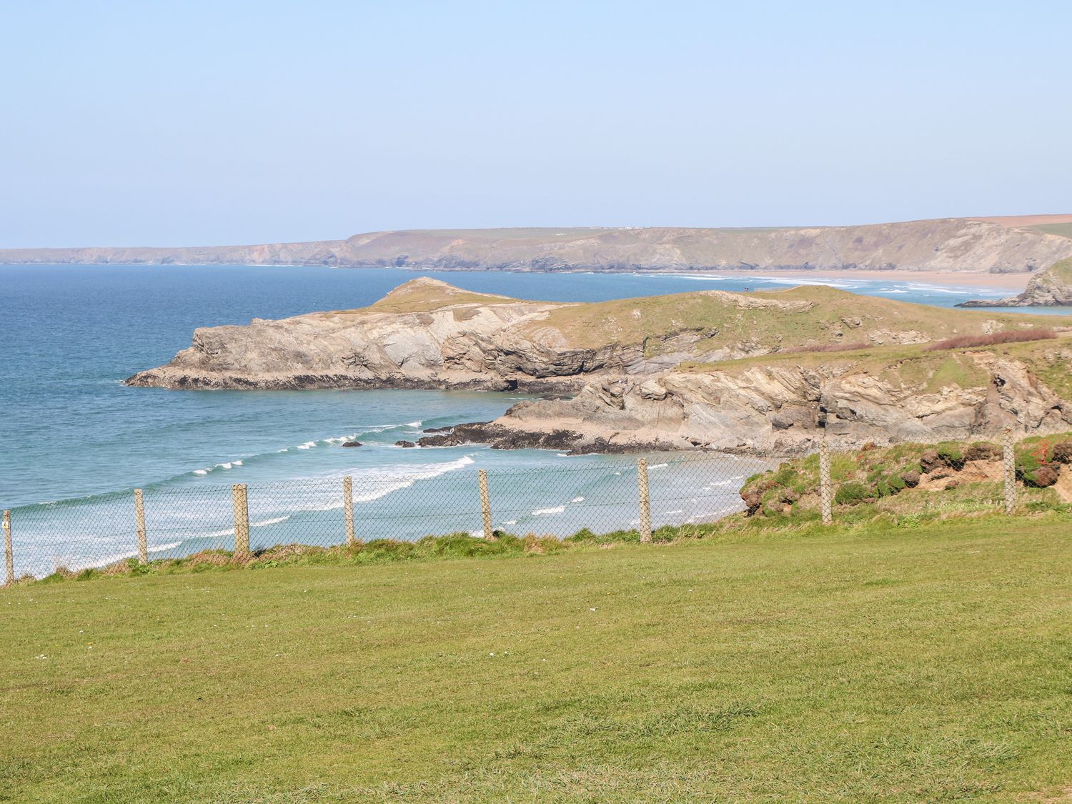 A coastal landscape with grassy cliffs and ocean waves at The Bright House in St Eval near St Columb Major