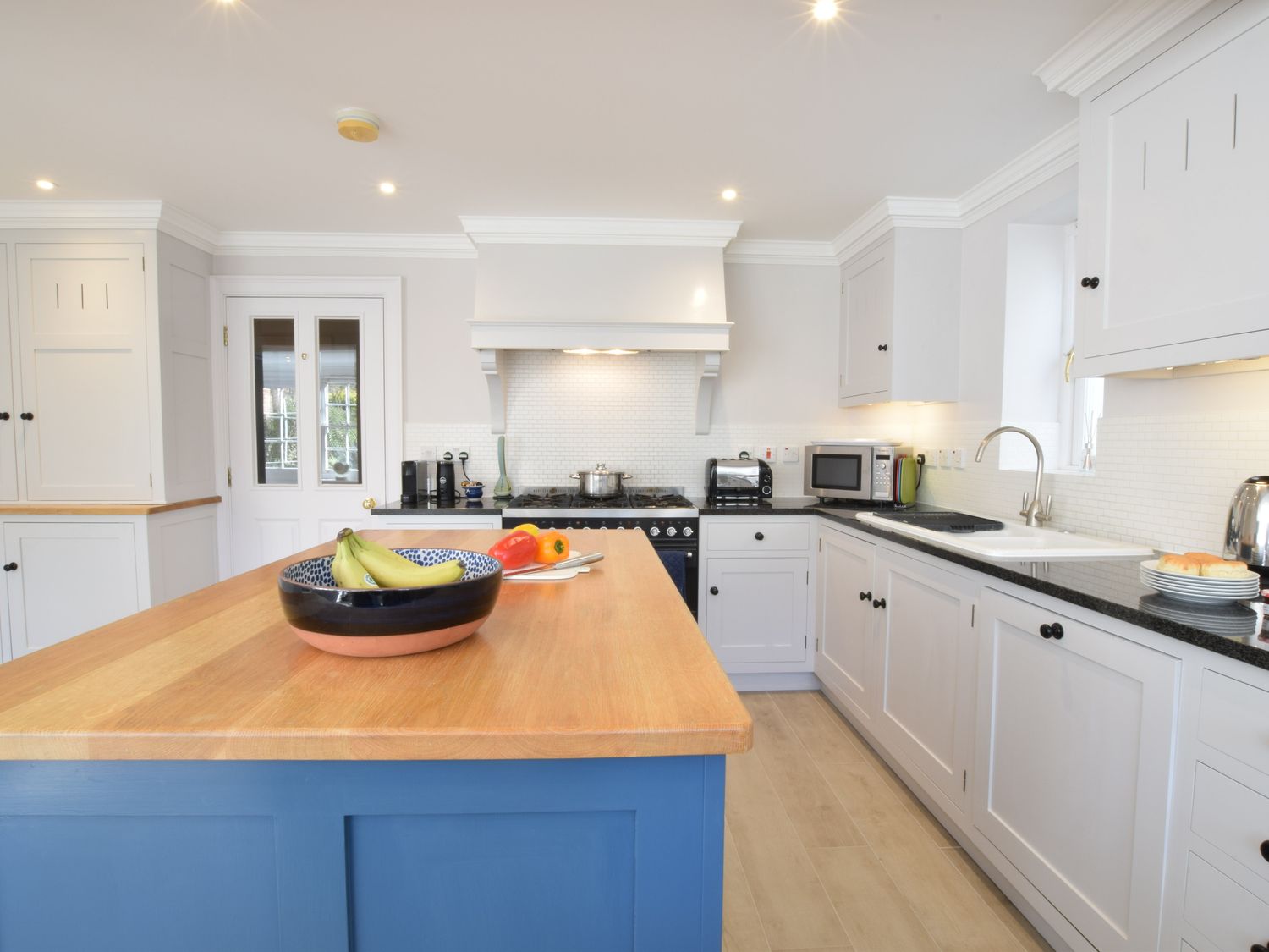 A kitchen with blue island and white cabinets at Seashells Aldeburgh in Aldeburgh