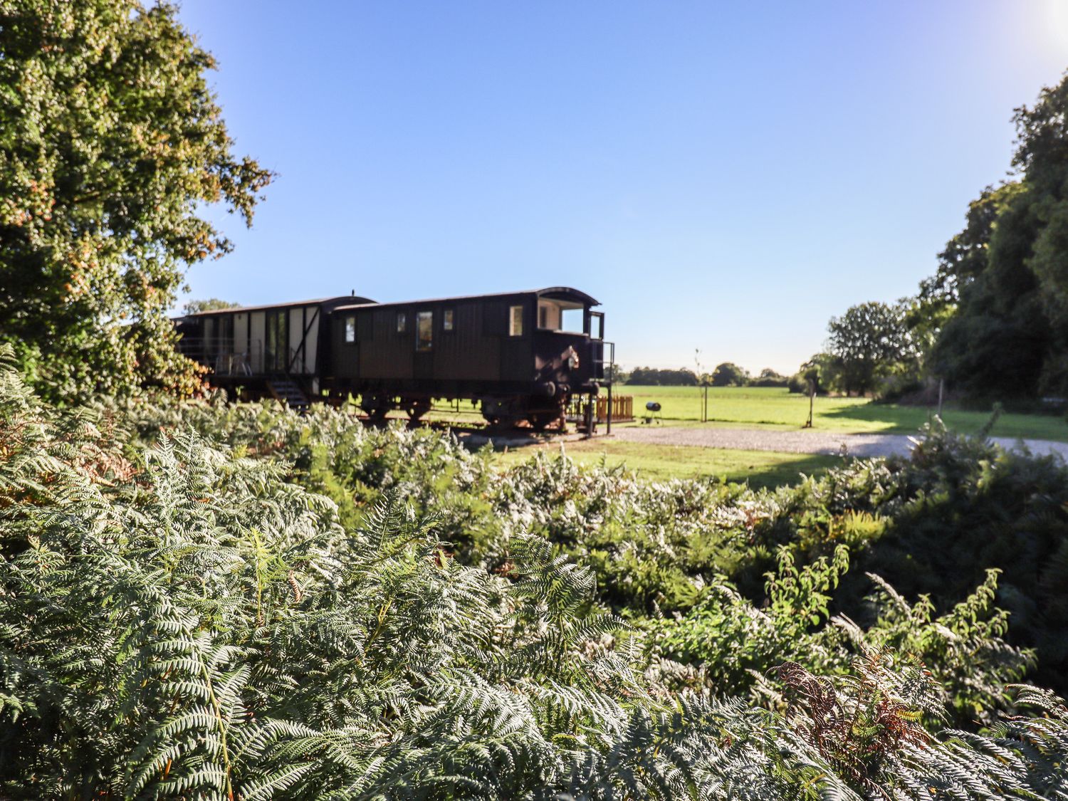 A railway wagon on a grassy field surrounded by trees and bushes at The Brake Wagon at High Barn Heritage in Greenstead Green near Halstead