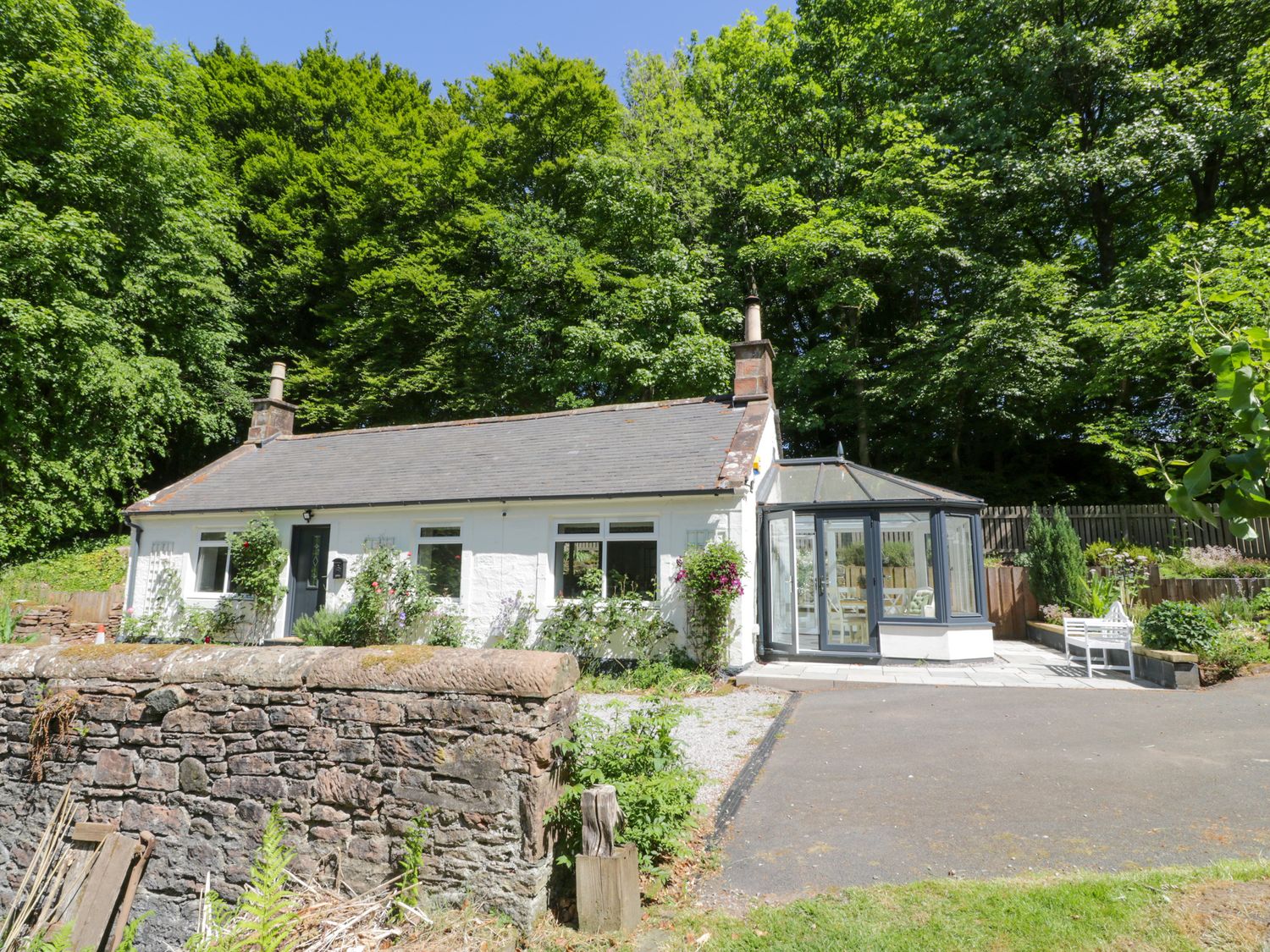 A house with a conservatory and garden area at Nithbank Cottage