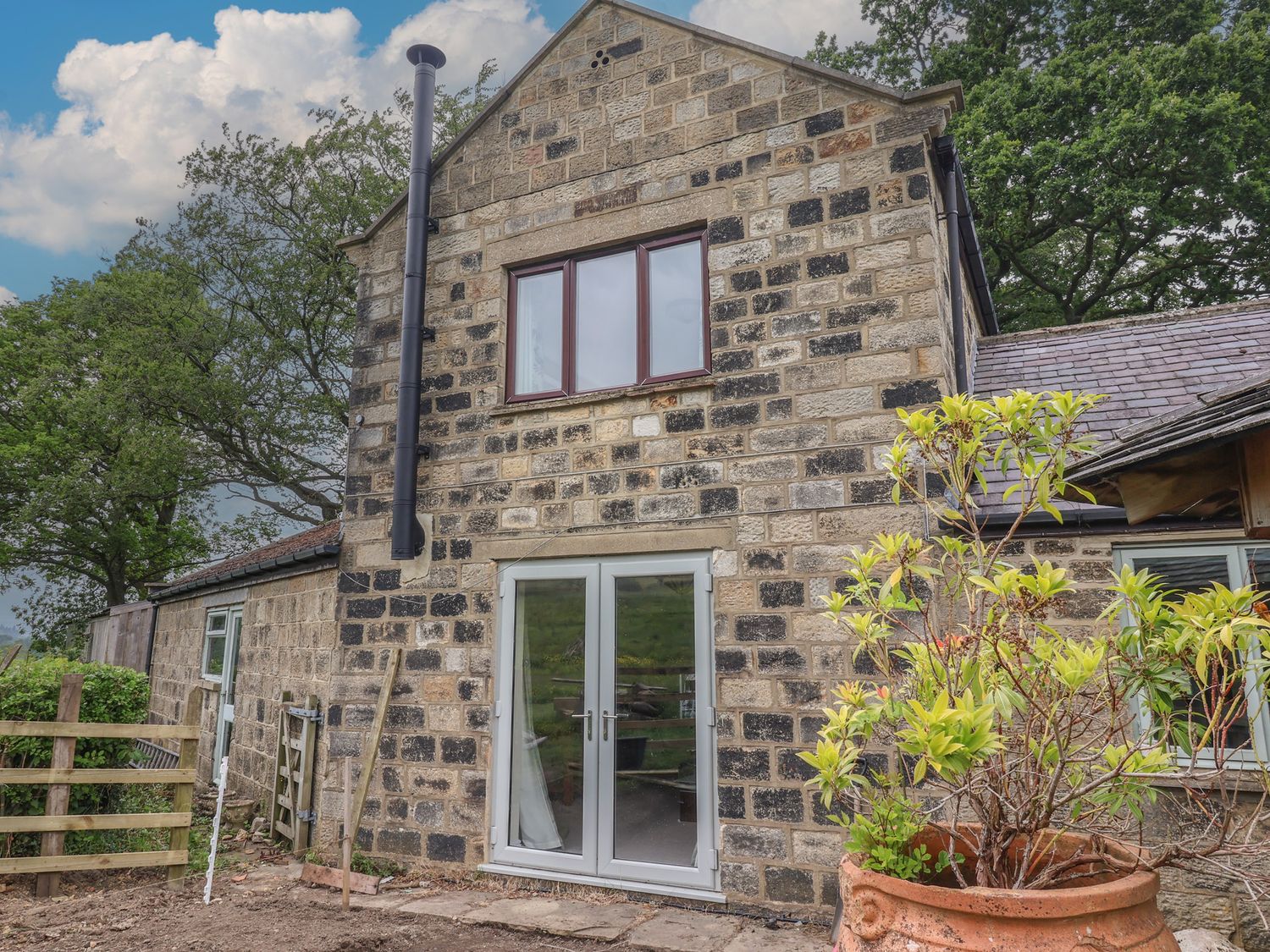 An outdoor view of a stone cottage with a door and windows at Cliffe House Cottage