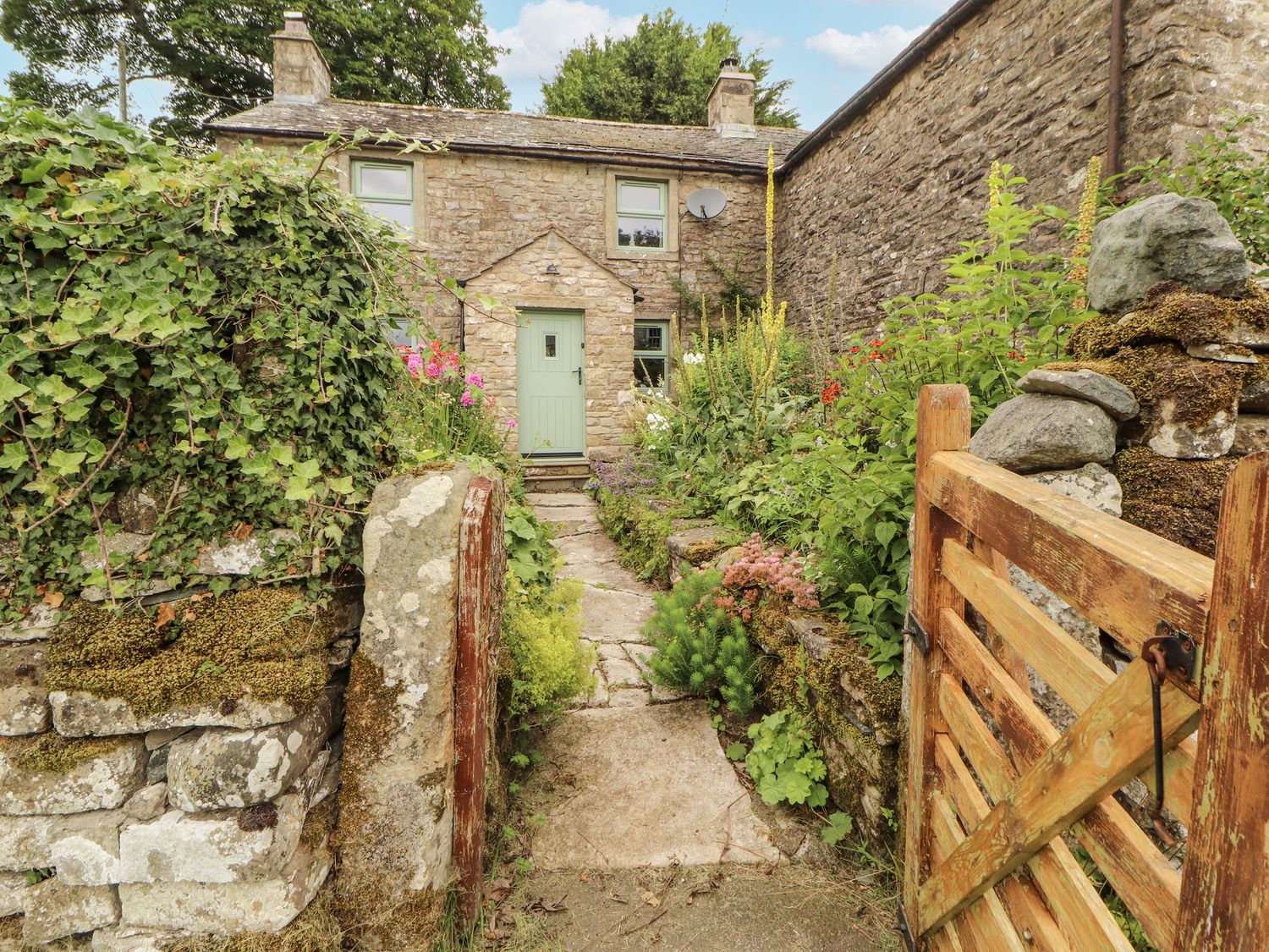 A stone cottage with a green door and garden path at White House in Shap