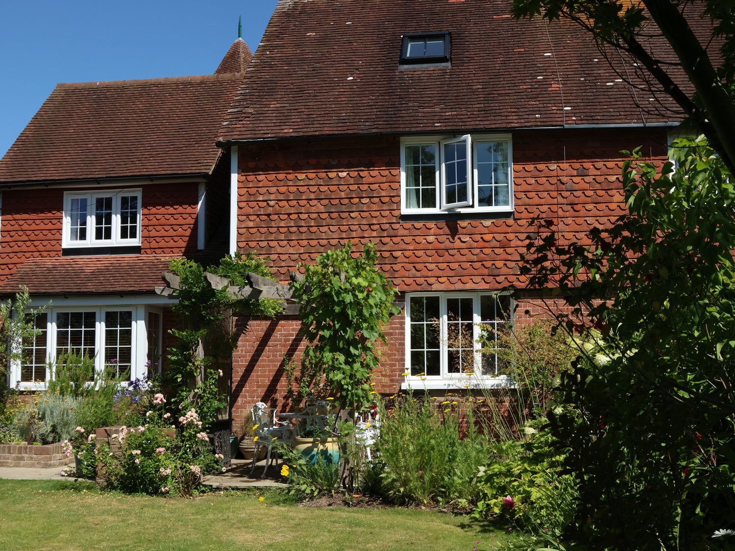 A house with garden and patio seating at Cherry Garden Cottage Sandhurst