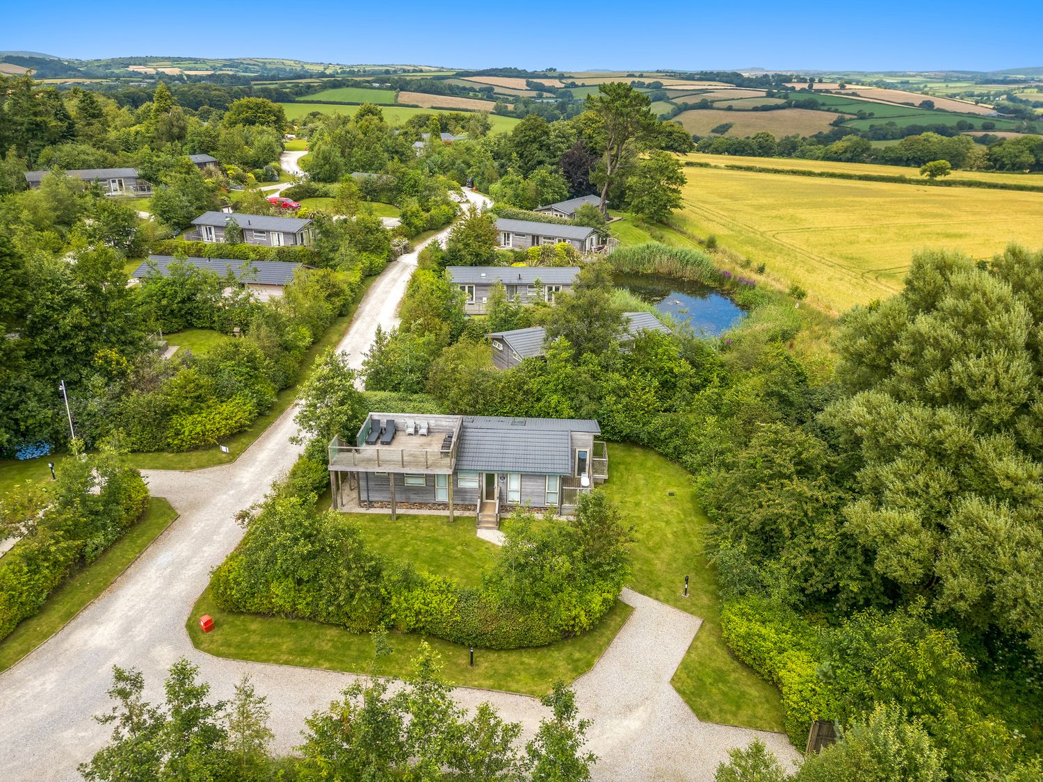 A cluster of single-story homes with surrounding trees and a small pond in a rural area at 2 Faraway Fields in Dobwalls