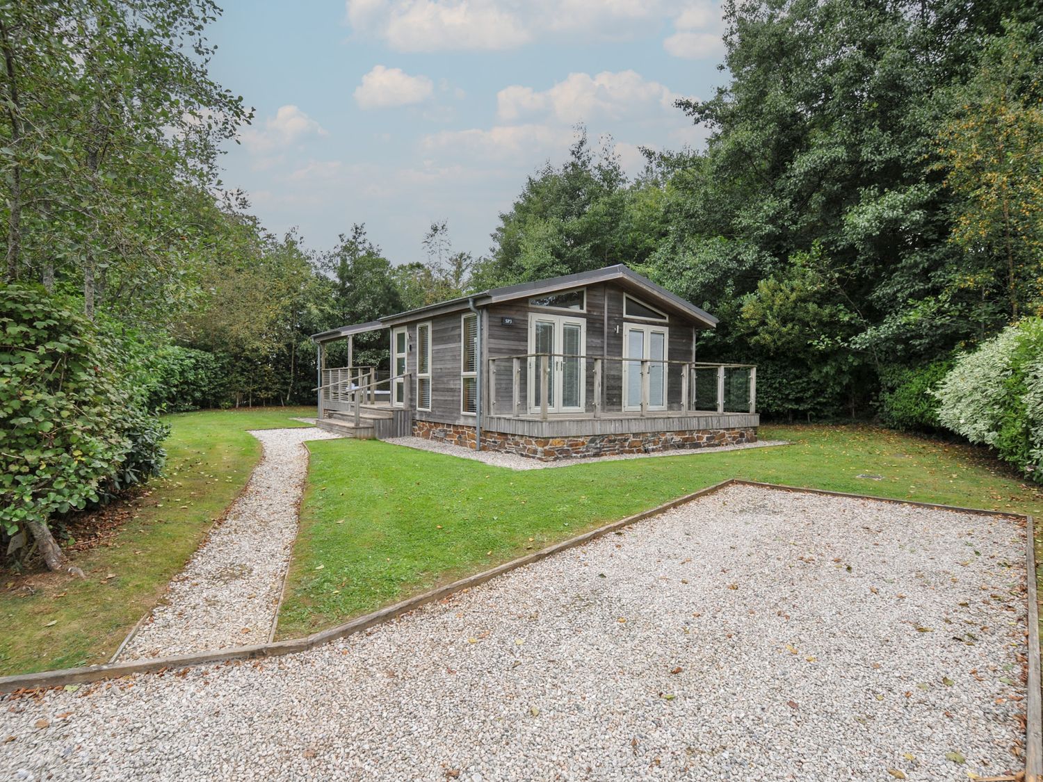 A house with a deck and pathway surrounded by grass and trees at 3 Southern Place in Dobwalls