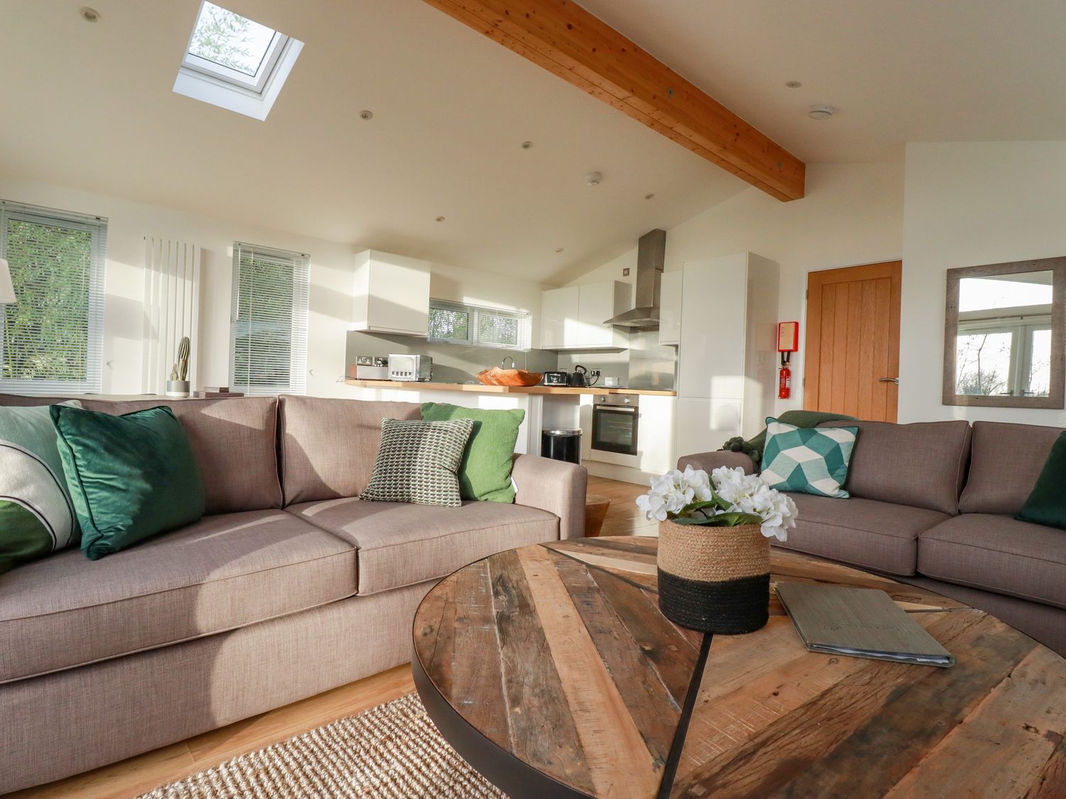 A living room with two sofas green cushions a wooden table and a kitchen in the background at 14 Horizon View in Dobwalls