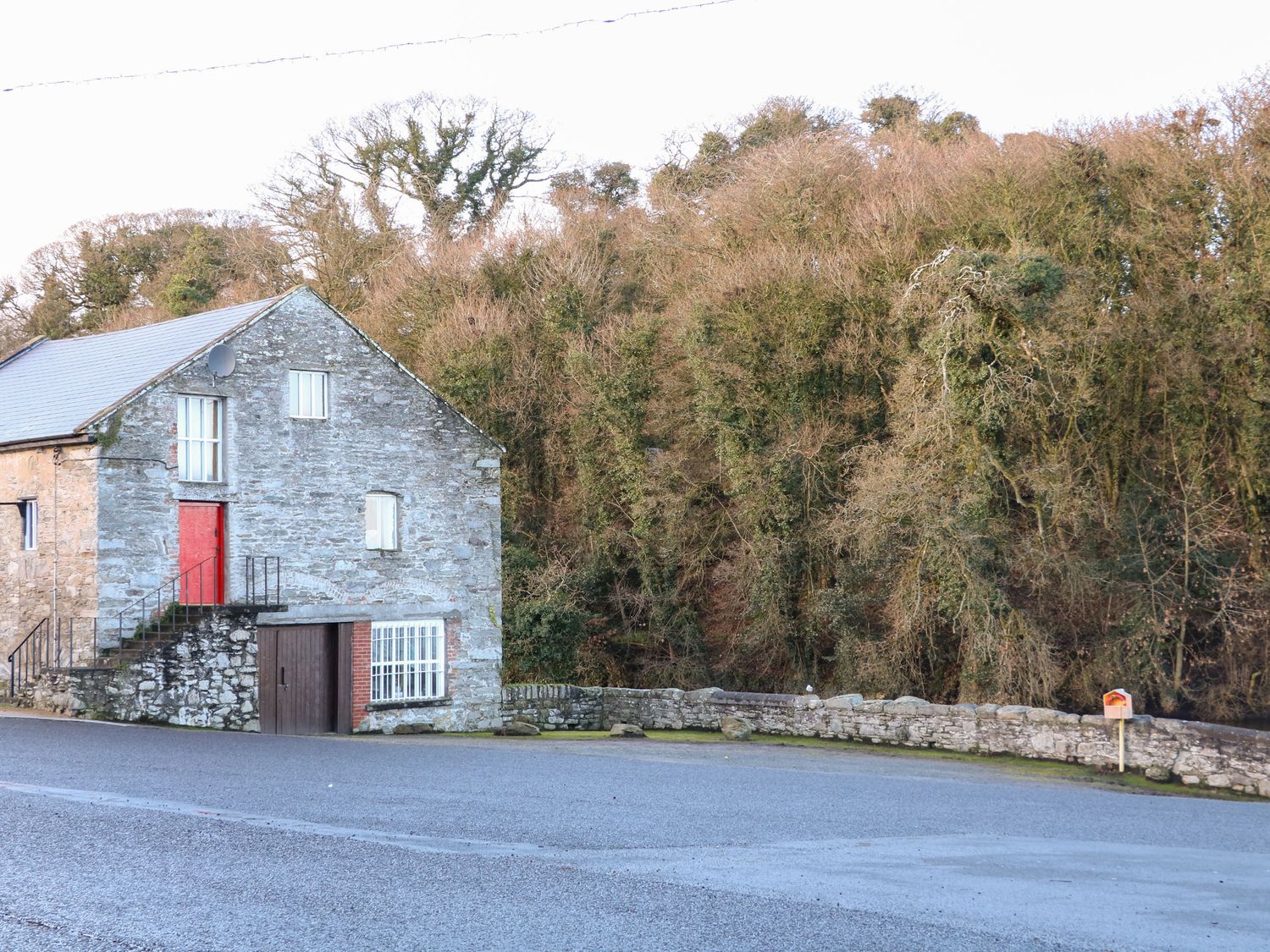 Stone house with red door near road and forested area at The River House in Ramelton County Donegal