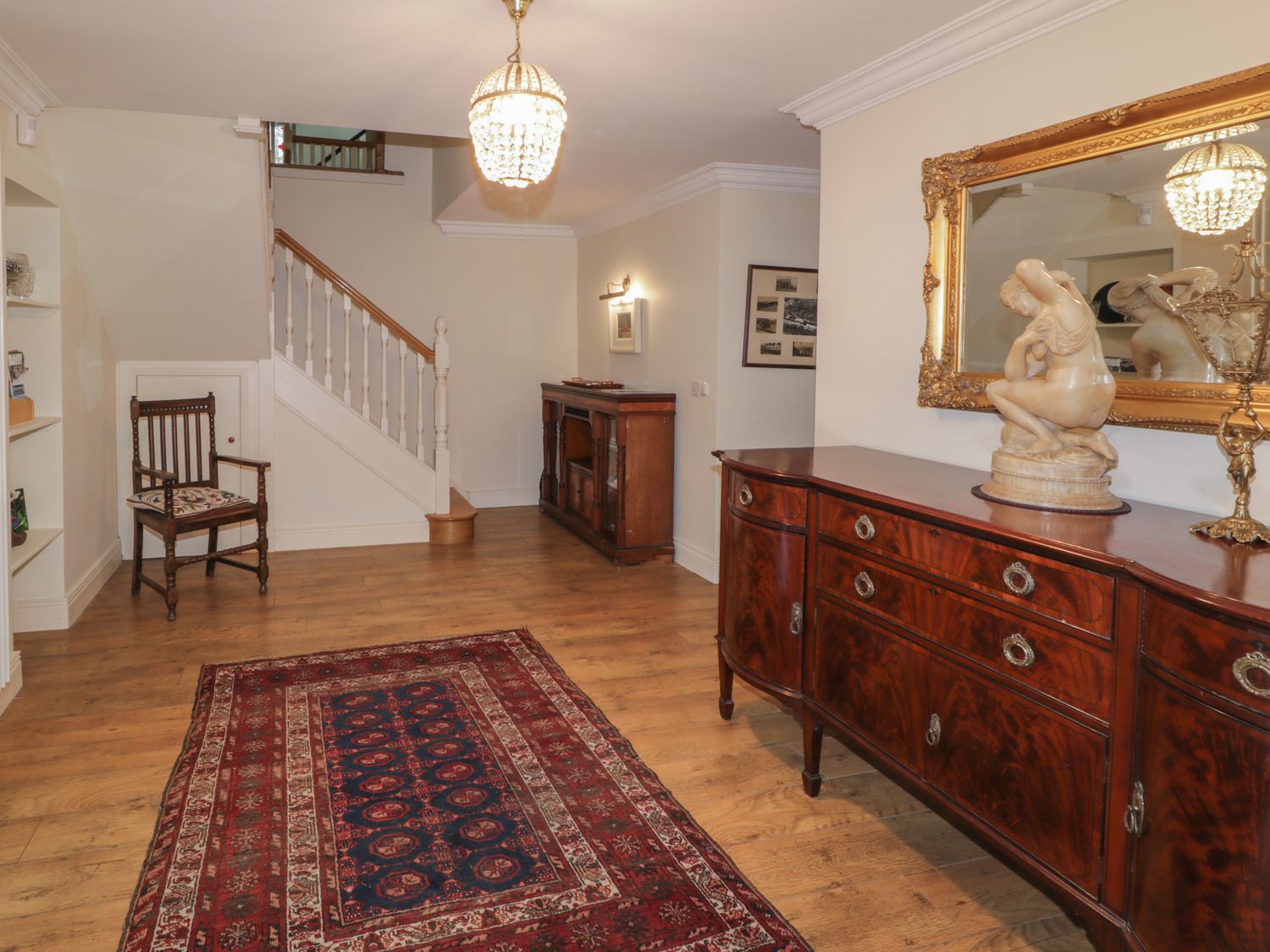 A hallway with wooden furniture a patterned rug a wooden chair stairs and a decorative lamp at The River House in Ramelton County Donegal