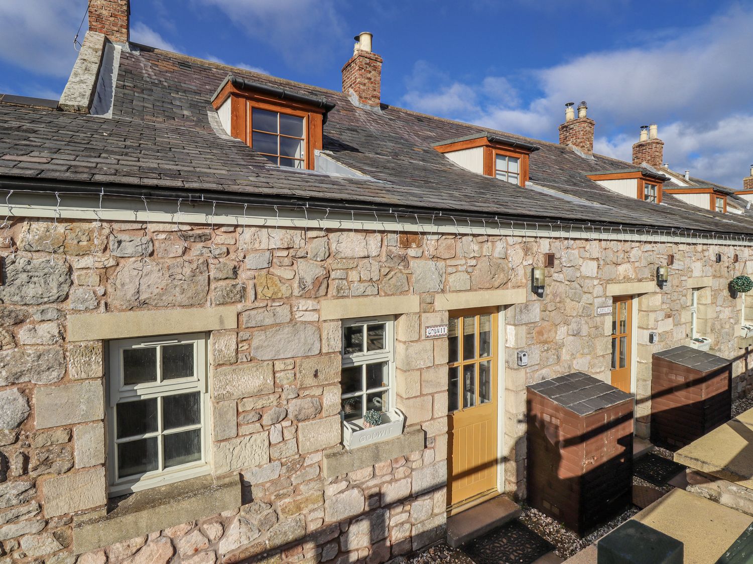 A stone cottage exterior with windows and doors at Heather Cottages - Godwit in Bamburgh