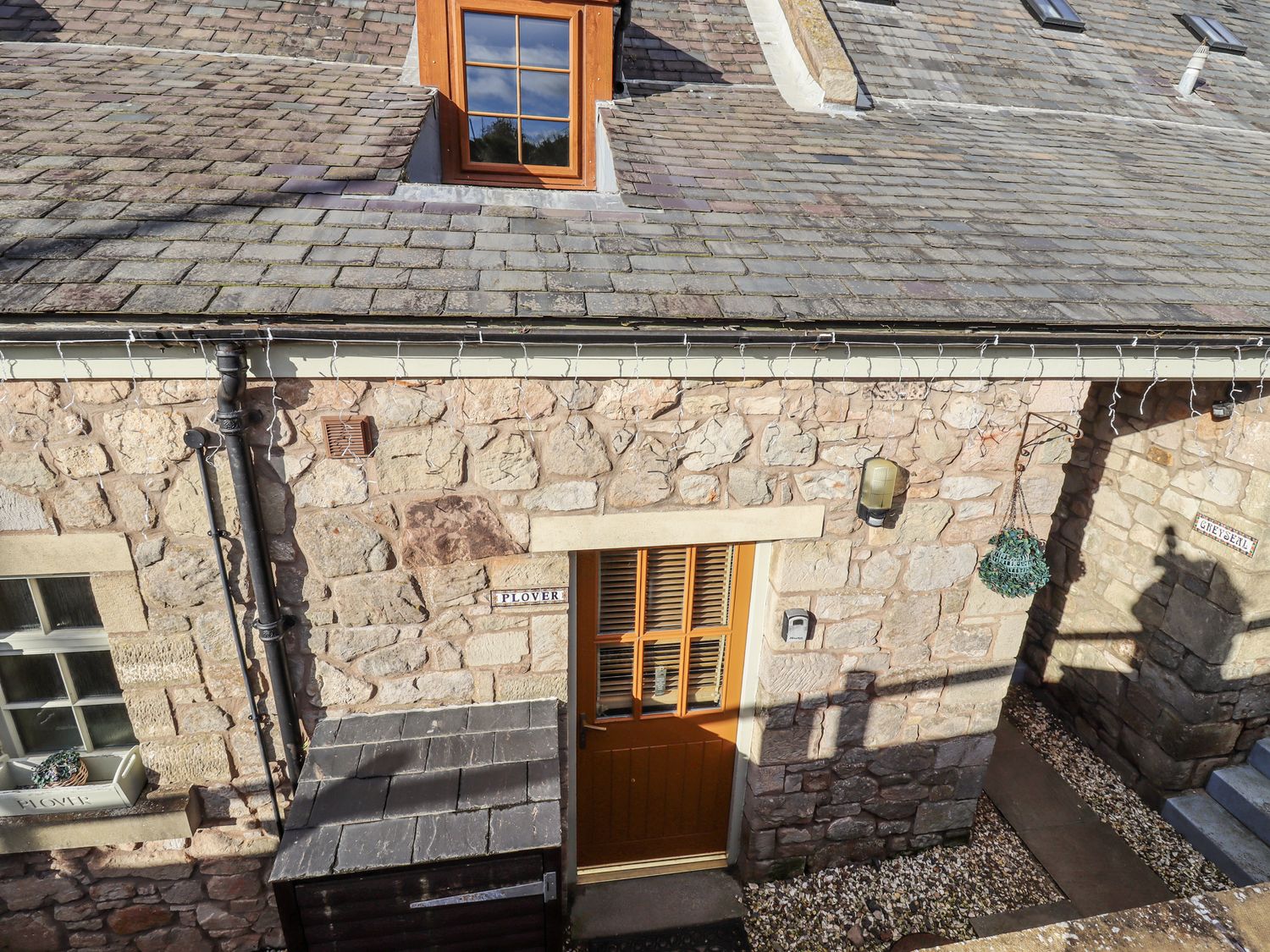A stone exterior with a door and window at Heather Cottages - Plover in Bamburgh