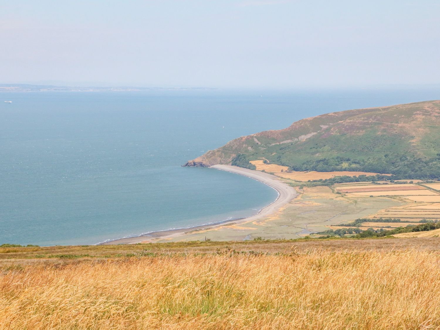 A coastal landscape with a curved beach fields and hills at Westholme Lodge in Minehead