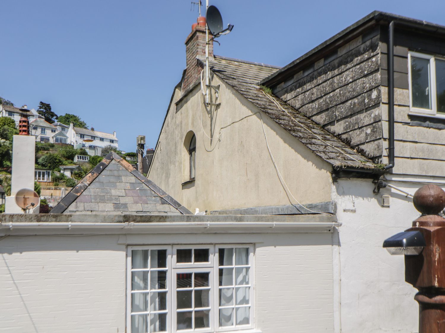 The exterior of connected houses with pitched roofs stone tiles chimney and windows at Alexandra Cottage in Looe