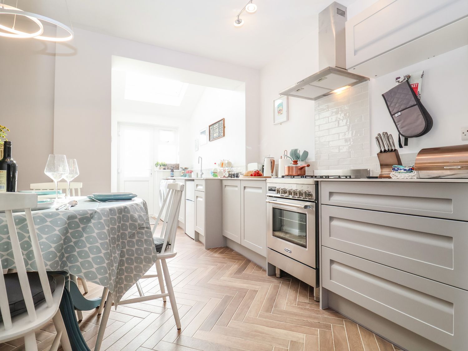 A kitchen with a dining table and chairs next to a stove and cabinets at Sea Mouse Cottage in Southwold
