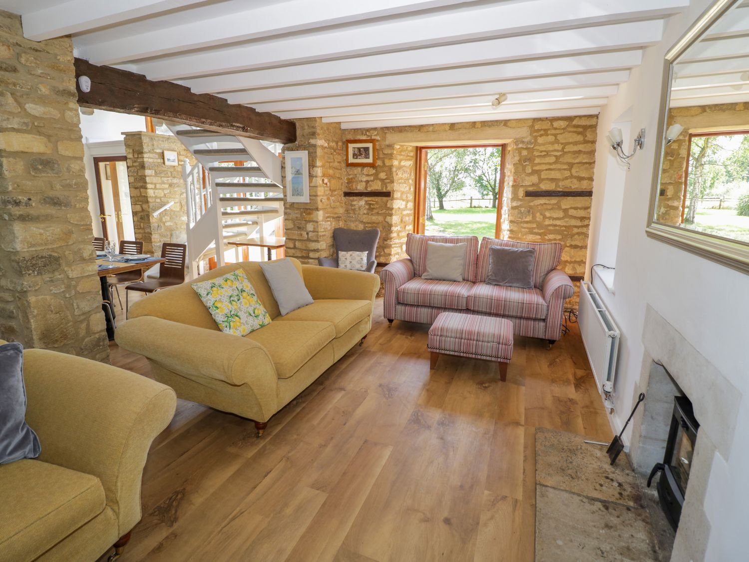 A living room with two sofas armchair fireplace and wooden floor at The Paddock in New Yatt near Witney