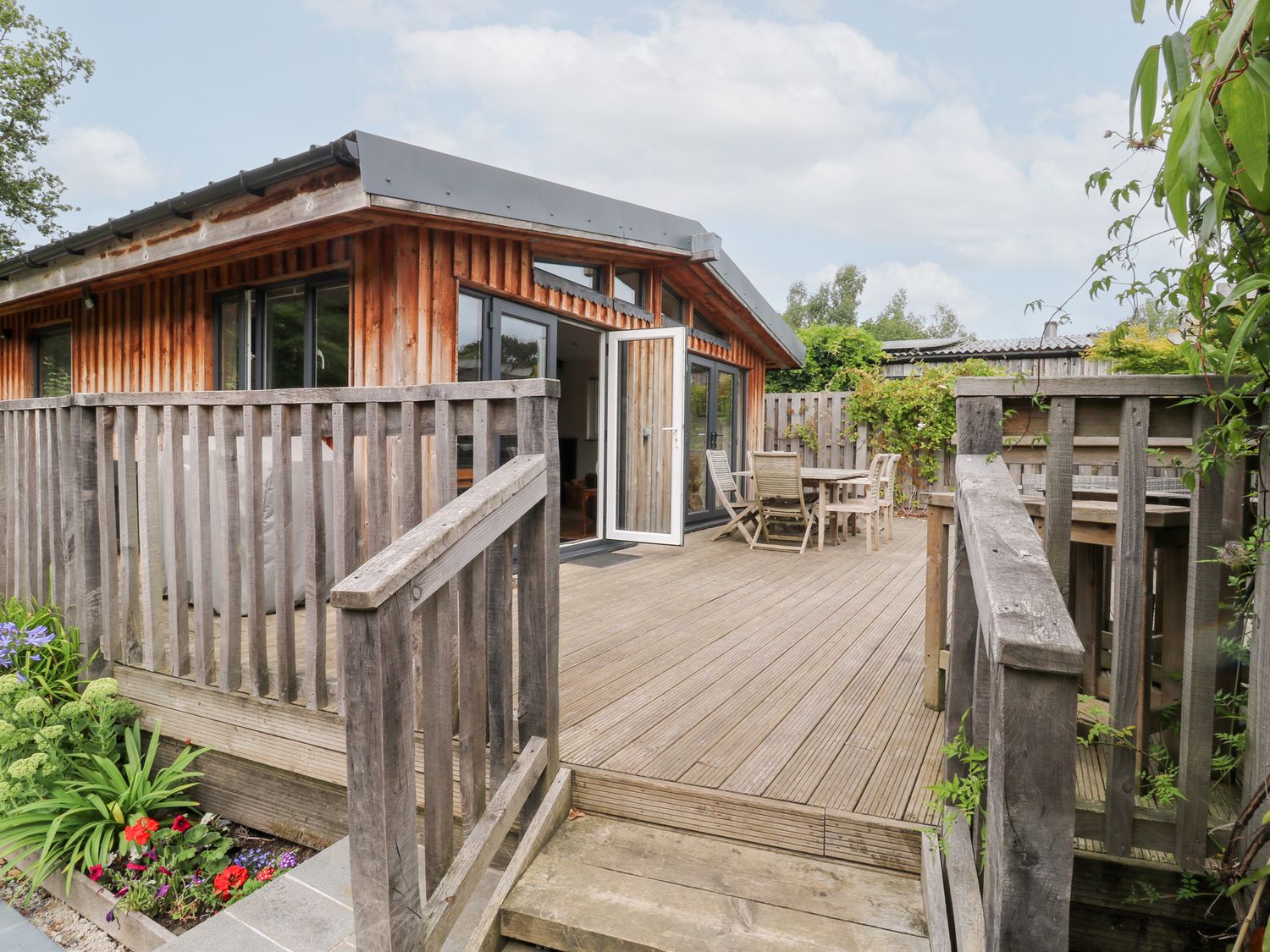 An outdoor area with decking and wooden furniture at Gloccamaura in Bovey Tracey