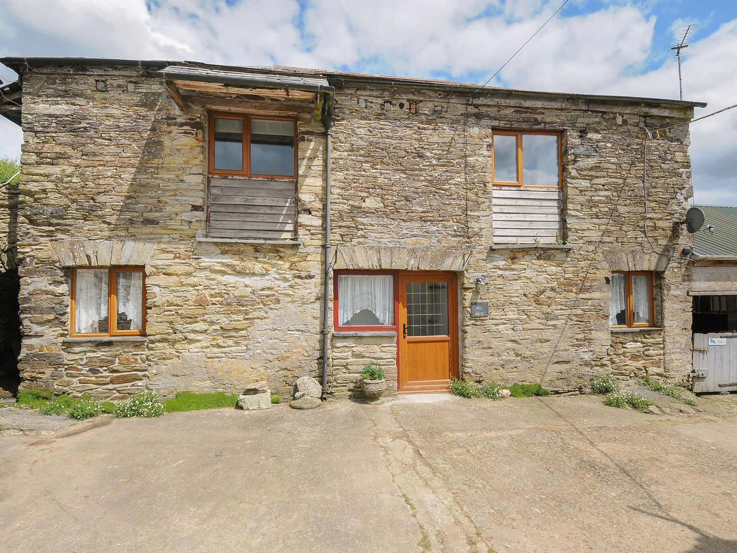 A stone house with four windows and a wooden door at Mill House in Lostwithiel near Pelynt
