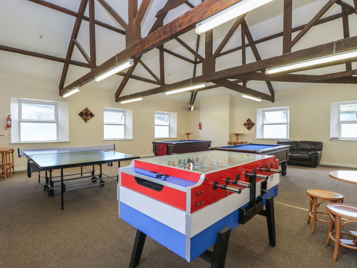 A game room with a foosball table ping pong table pool tables and seating at Wrens Nest Manorcombe in Honicombe Park near Gunnislake