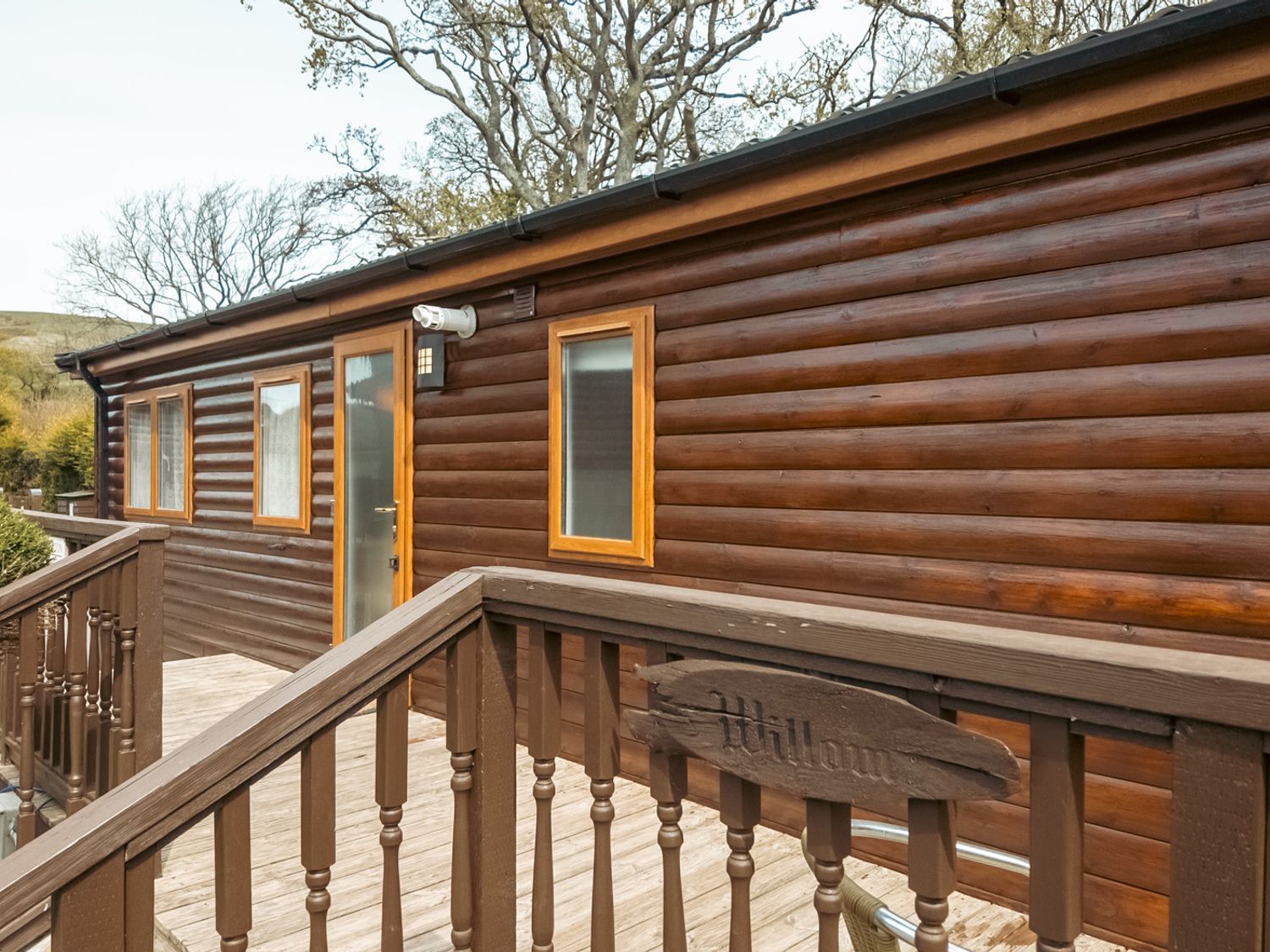 A wooden cabin exterior with a deck and steps at Willow in Swanage
