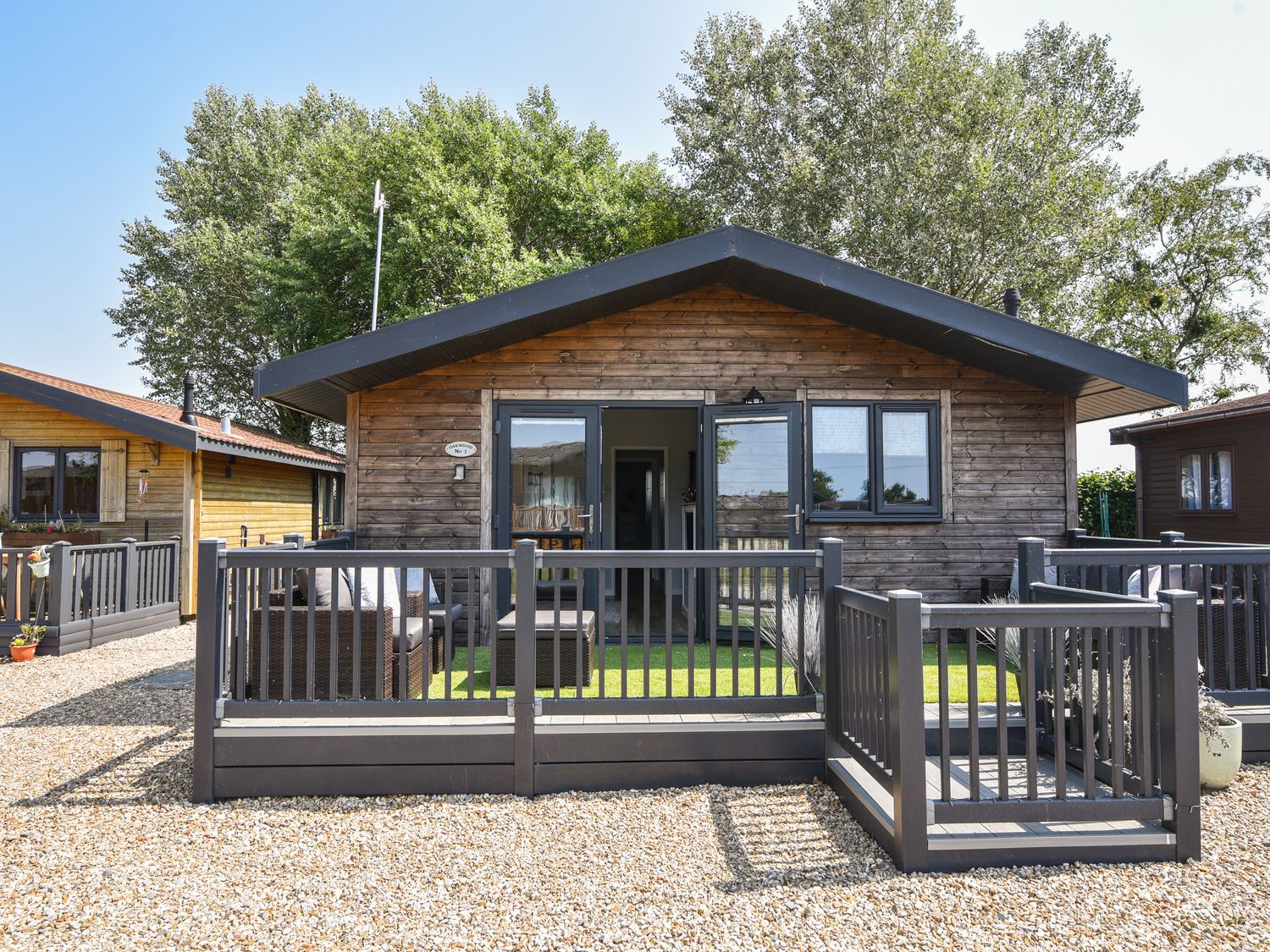 A wooden cabin with a black railing deck and outdoor furniture at Oakwood 2 @ Pinewood Retreat in Pinewood
