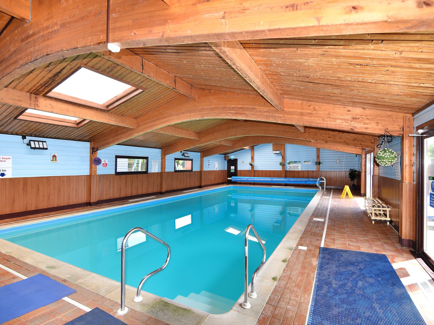 An indoor swimming pool with wooden ceiling and blue walls at Oakwood 2 @ Pinewood Retreat in Pinewood