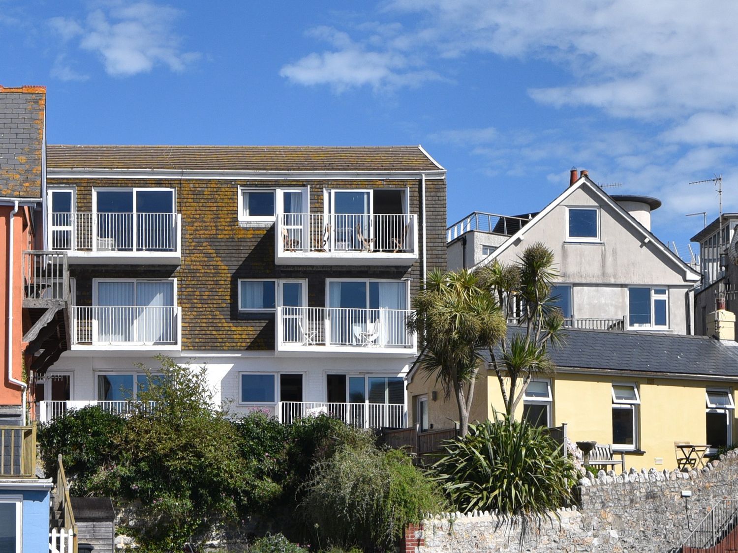A group of residential buildings with balconies and greenery in front at 3 Bay View Court in Lyme Regis
