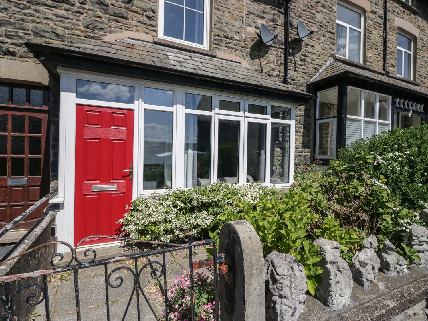 A front entrance with a red door and flowers at Badgers, Sedbergh, Yorkshire Dales