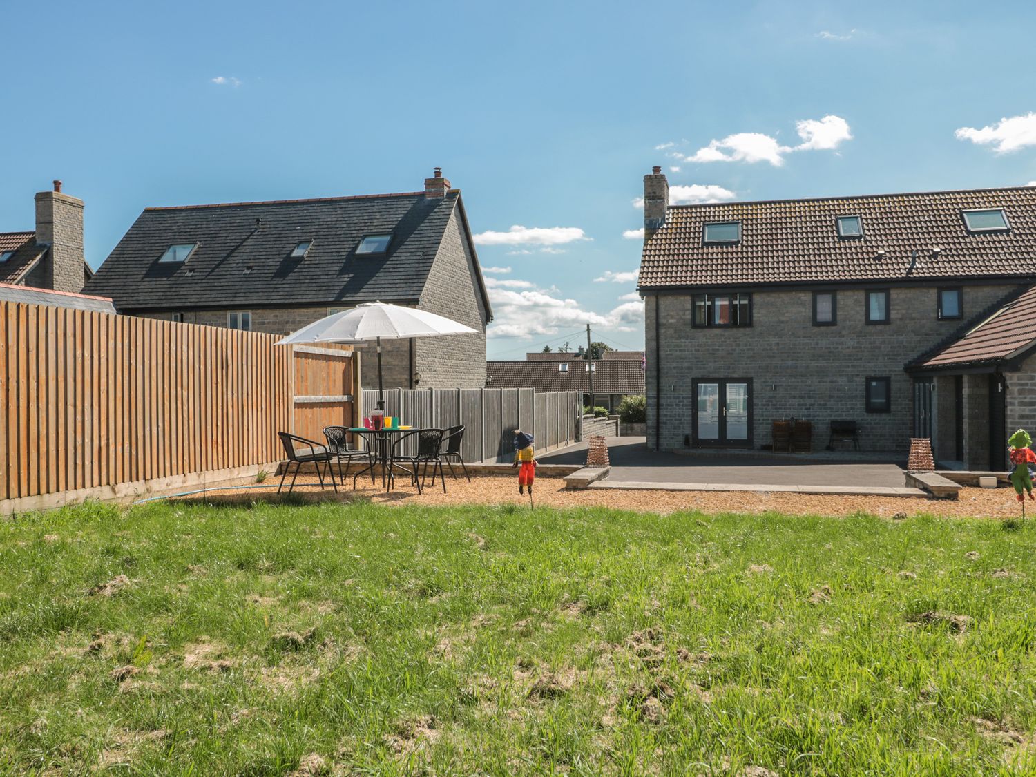 A backyard with a table and chairs under an umbrella and houses in the background at Homeland in Somerton