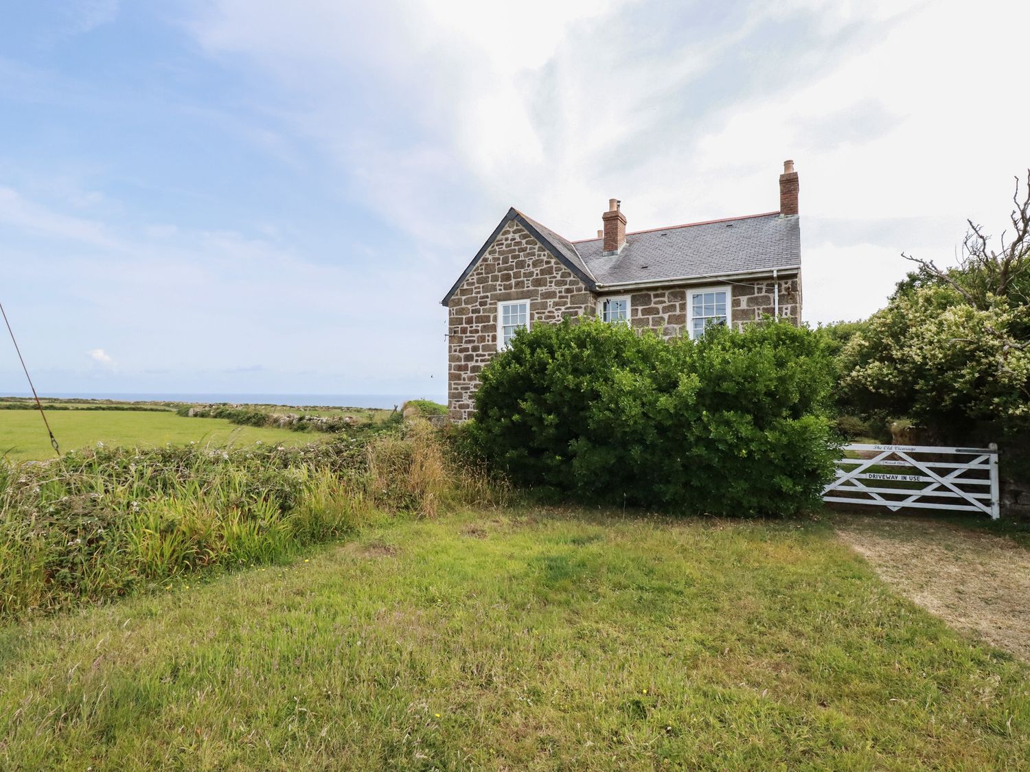 A stone house with a slate roof surrounded by grass and bushes at The Old Vicarage in Morvah