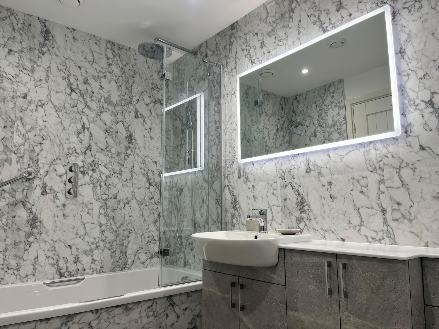 A bathroom with a bathtub a shower a sink and a lighted mirror at Pen-Y-Les in Wadebridge