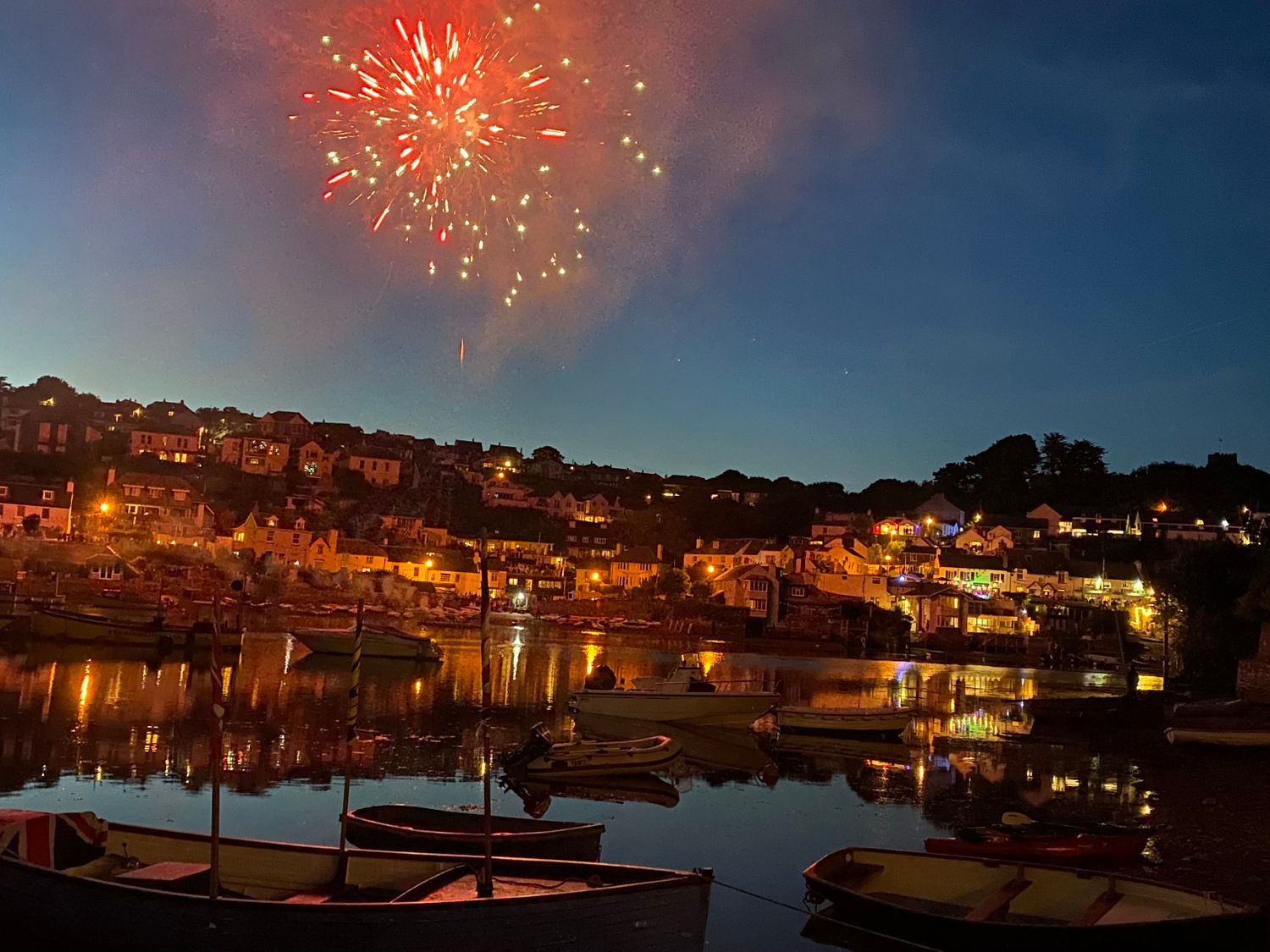 Fireworks over a harbor with boats and houses lit up at night at Bridgend Barn in Newton Ferrers