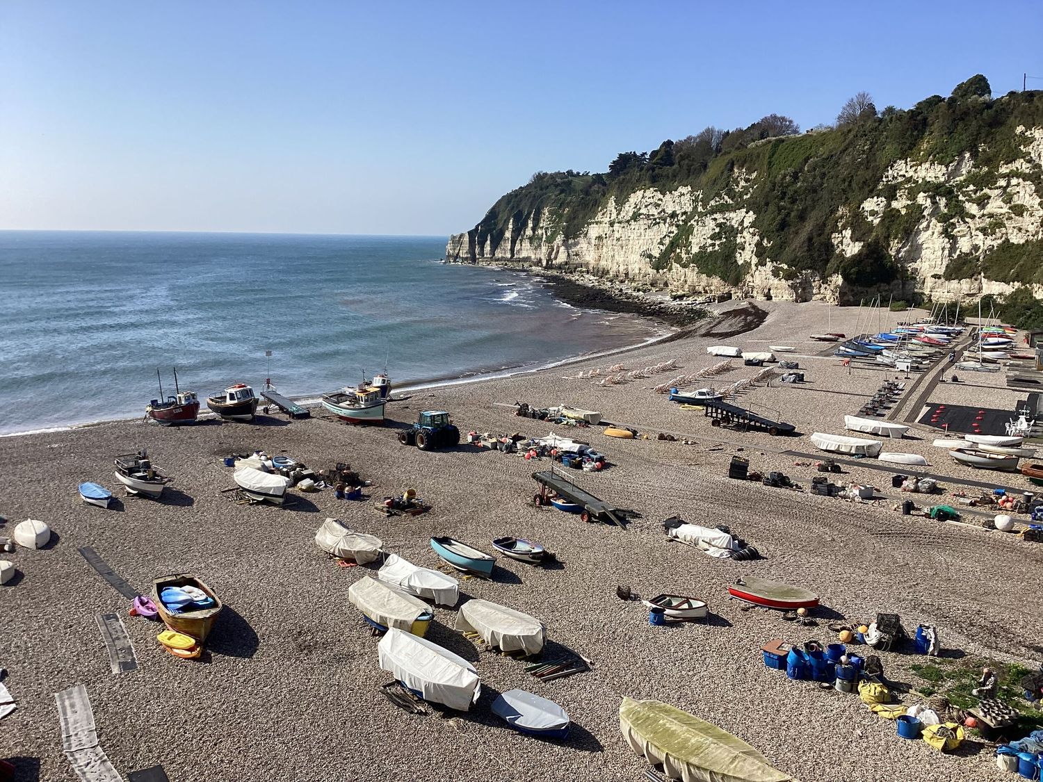 A pebble beach with boats and equipment near cliffs by the sea at Bridge Cottage in Dalwood
