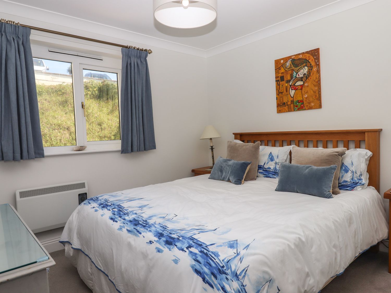 A bedroom with a double bed with blue and white bedding and blue curtains at 14 Burgh Island Causeway in Bigbury-On-Sea