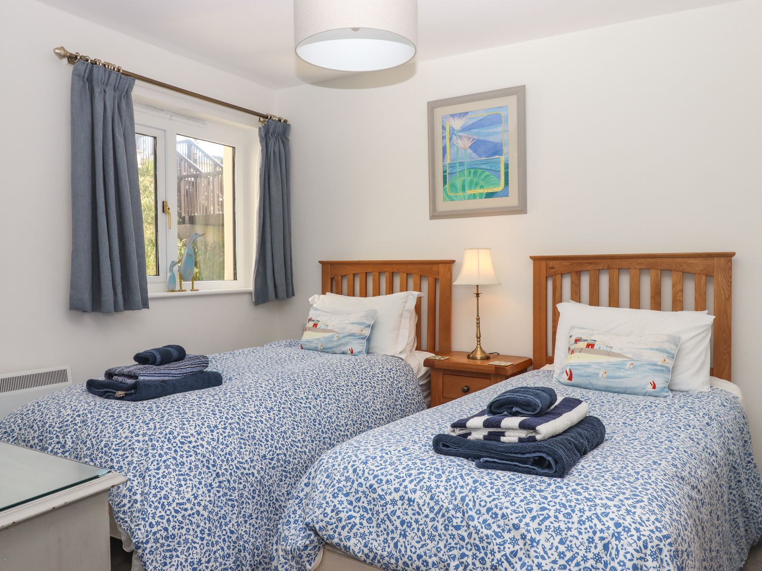 A bedroom with two single beds with blue patterned bedding and folded towels on each bed at 14 Burgh Island Causeway in Bigbury-On-Sea
