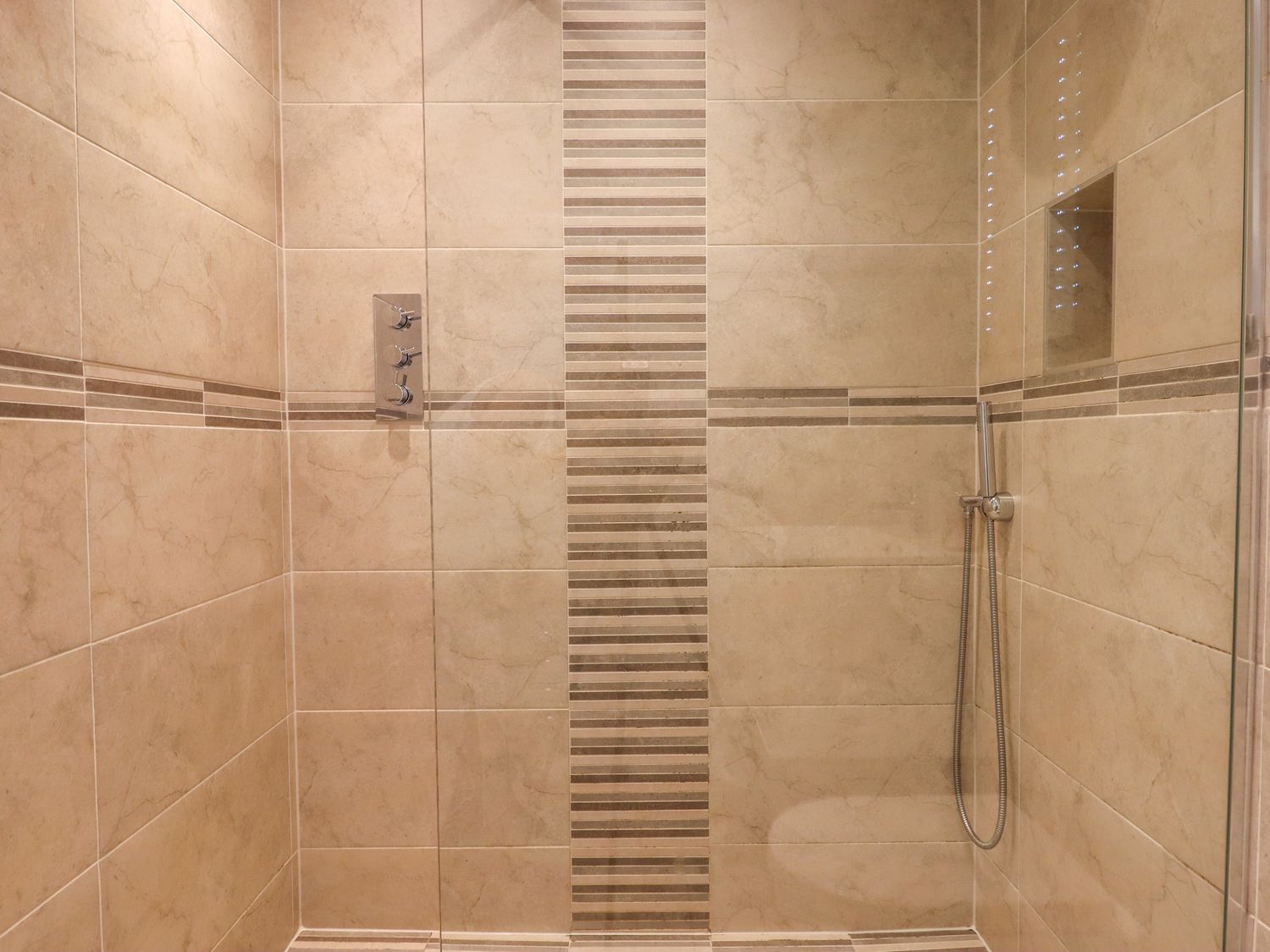 A tiled walk in shower with a handheld showerhead and built in controls at 14 Burgh Island Causeway Bigbury-On-Sea