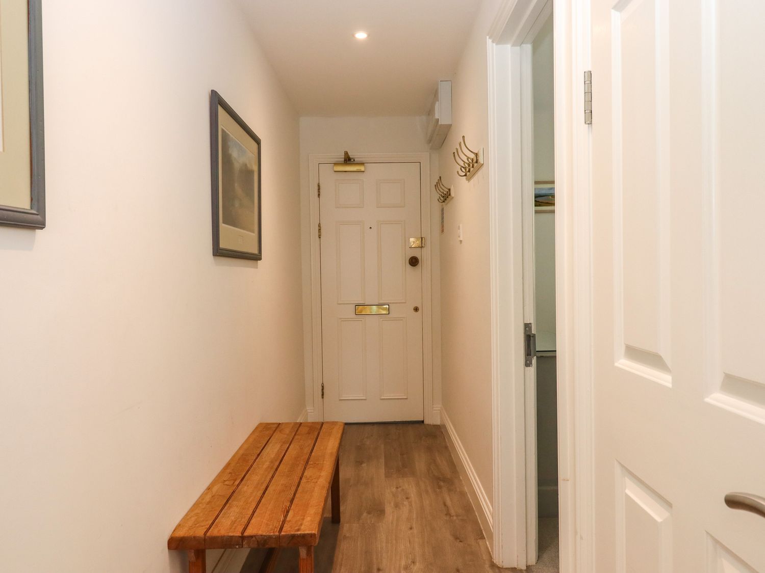 A narrow hallway with a wooden bench and hooks on the wall at 14 Burgh Island Causeway in Bigbury-On-Sea