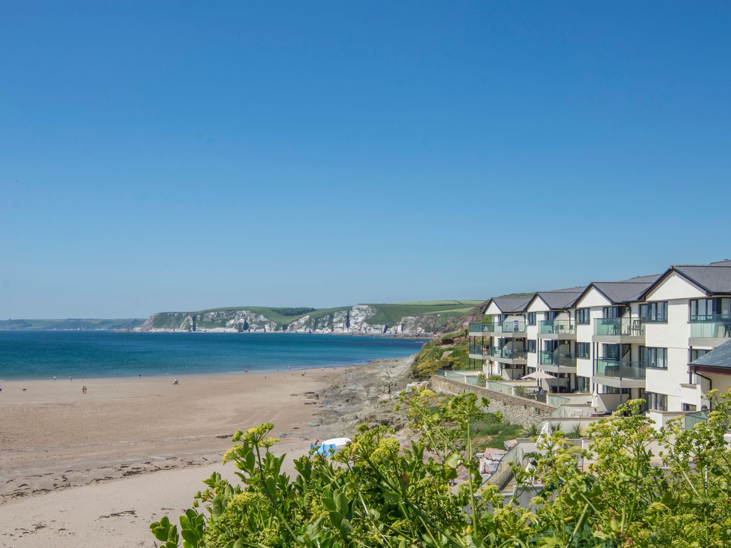 A beach with sand and rocks beside a row of buildings overlooking the sea at 14 Burgh Island Causeway Bigbury-On-Sea