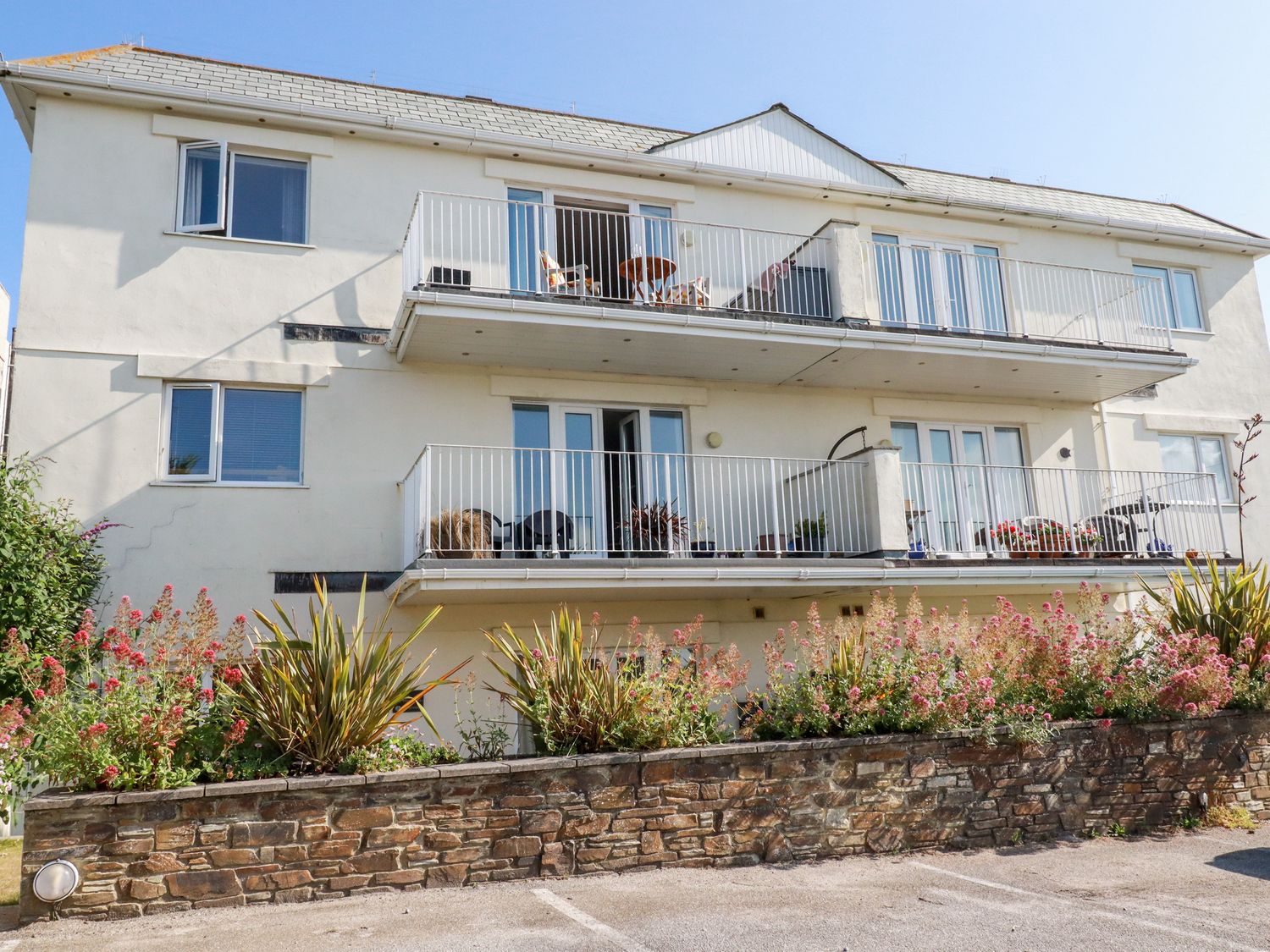 A three story building with balconies and plants in front at Far Horizons in Newquay