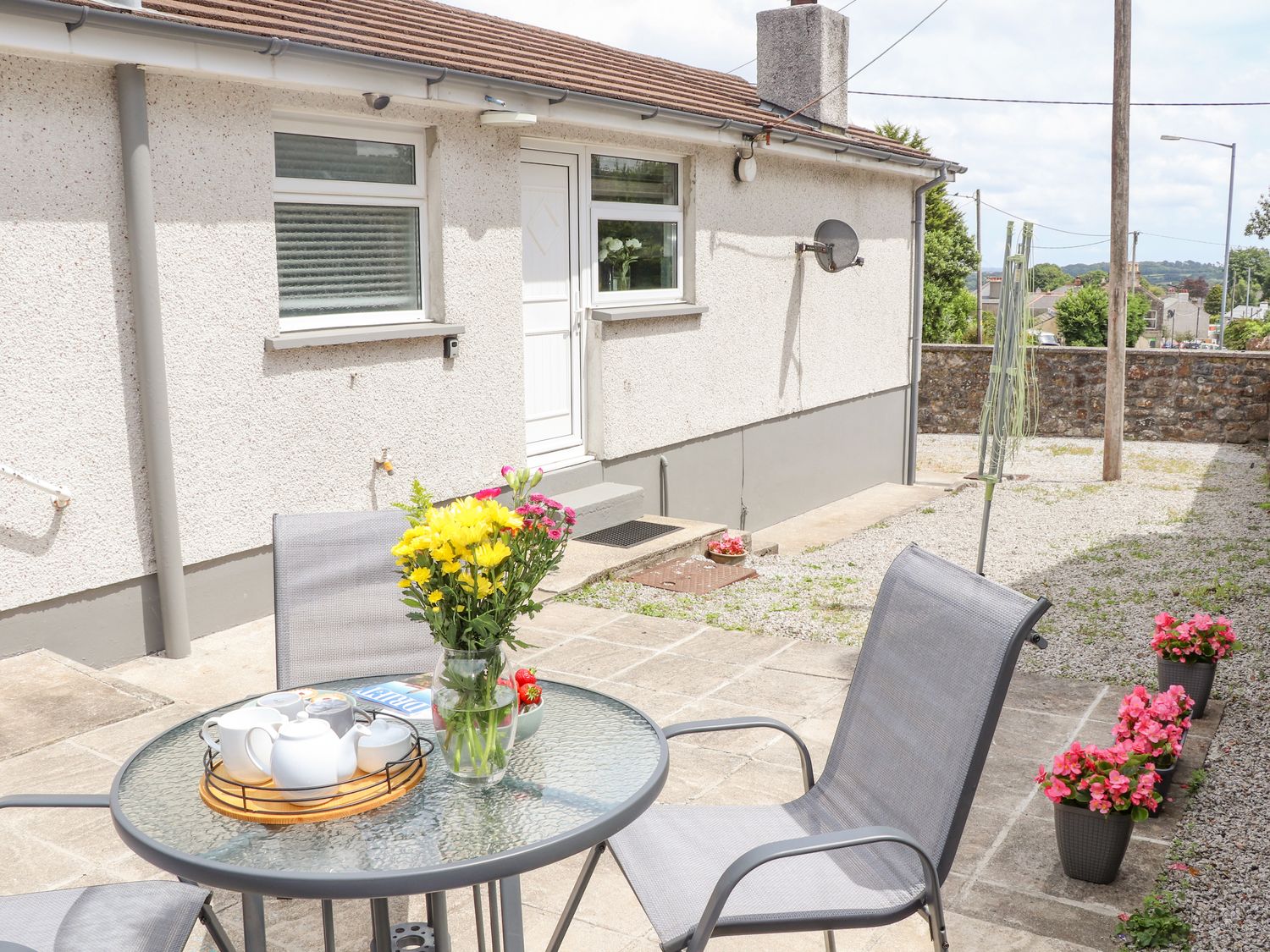 A patio area with a round glass table and two chairs outside a bungalow at Apple Tree Bungalow in Lanner