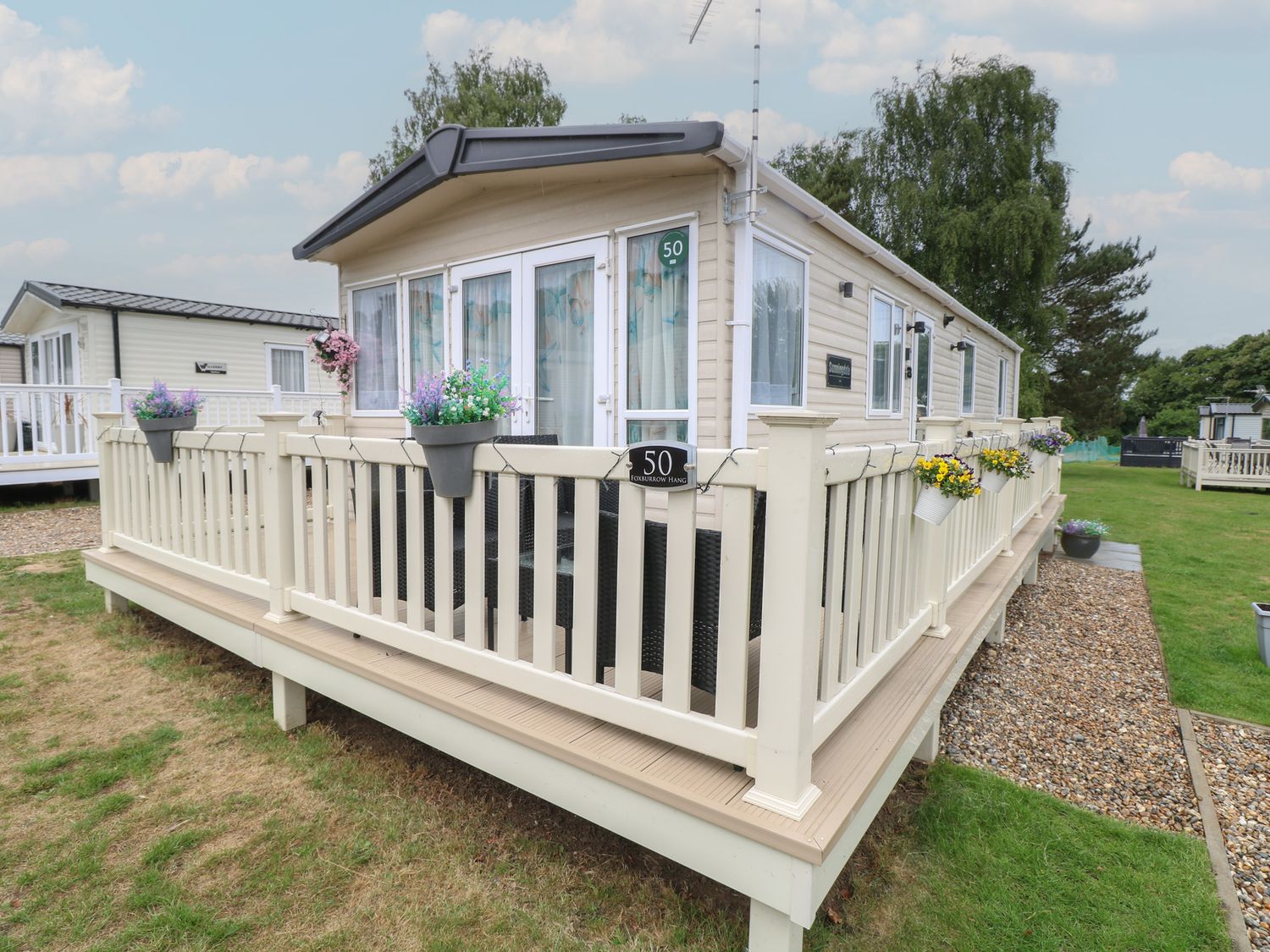 An outdoor area with a mobile home and deck at Seashell Lodge, 50 Foxburrow Hang in Belton, Norfolk