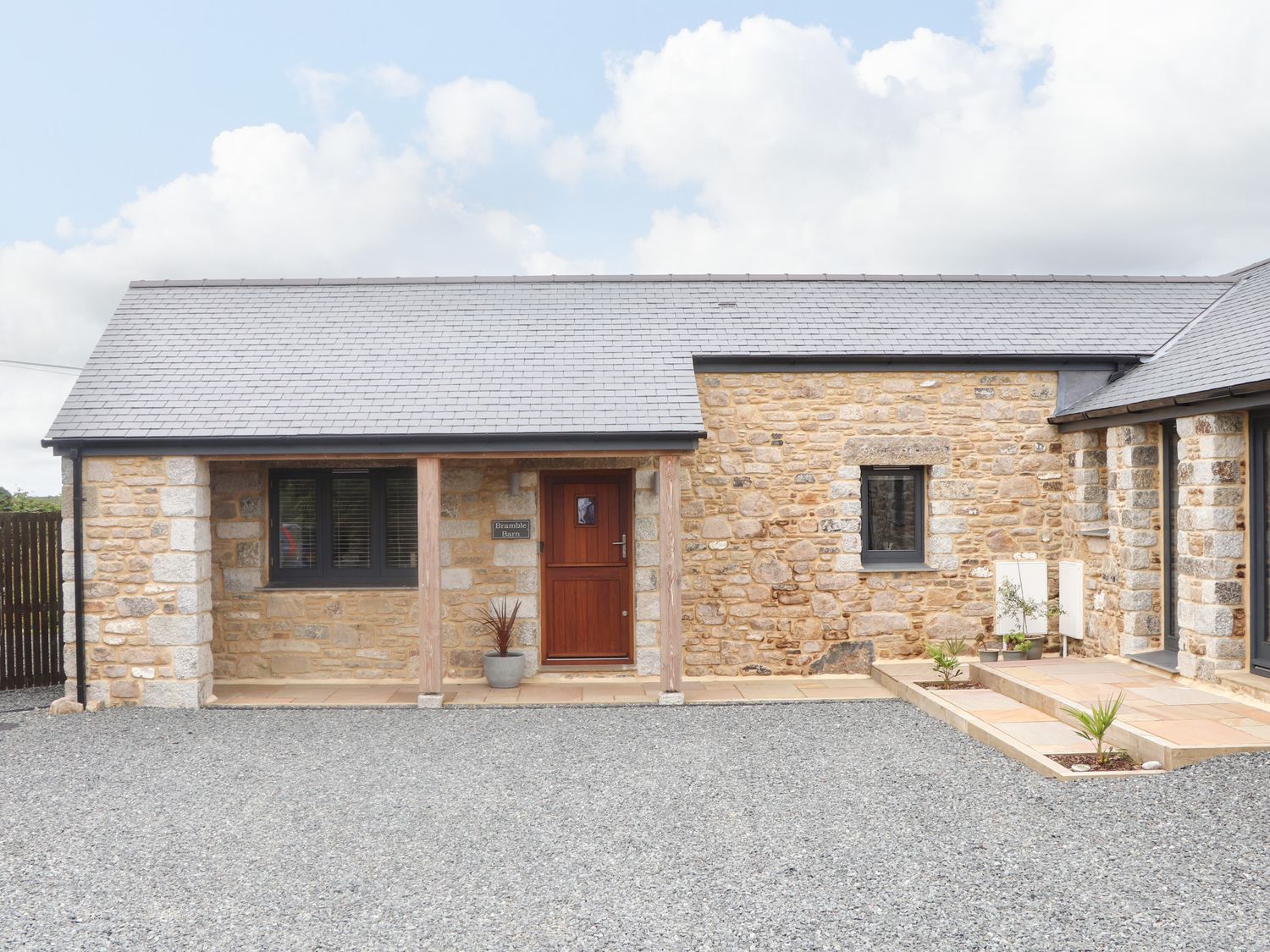 Stone exterior building with wooden door and windows with gravel ground in front at Bramble Barn in St Ives