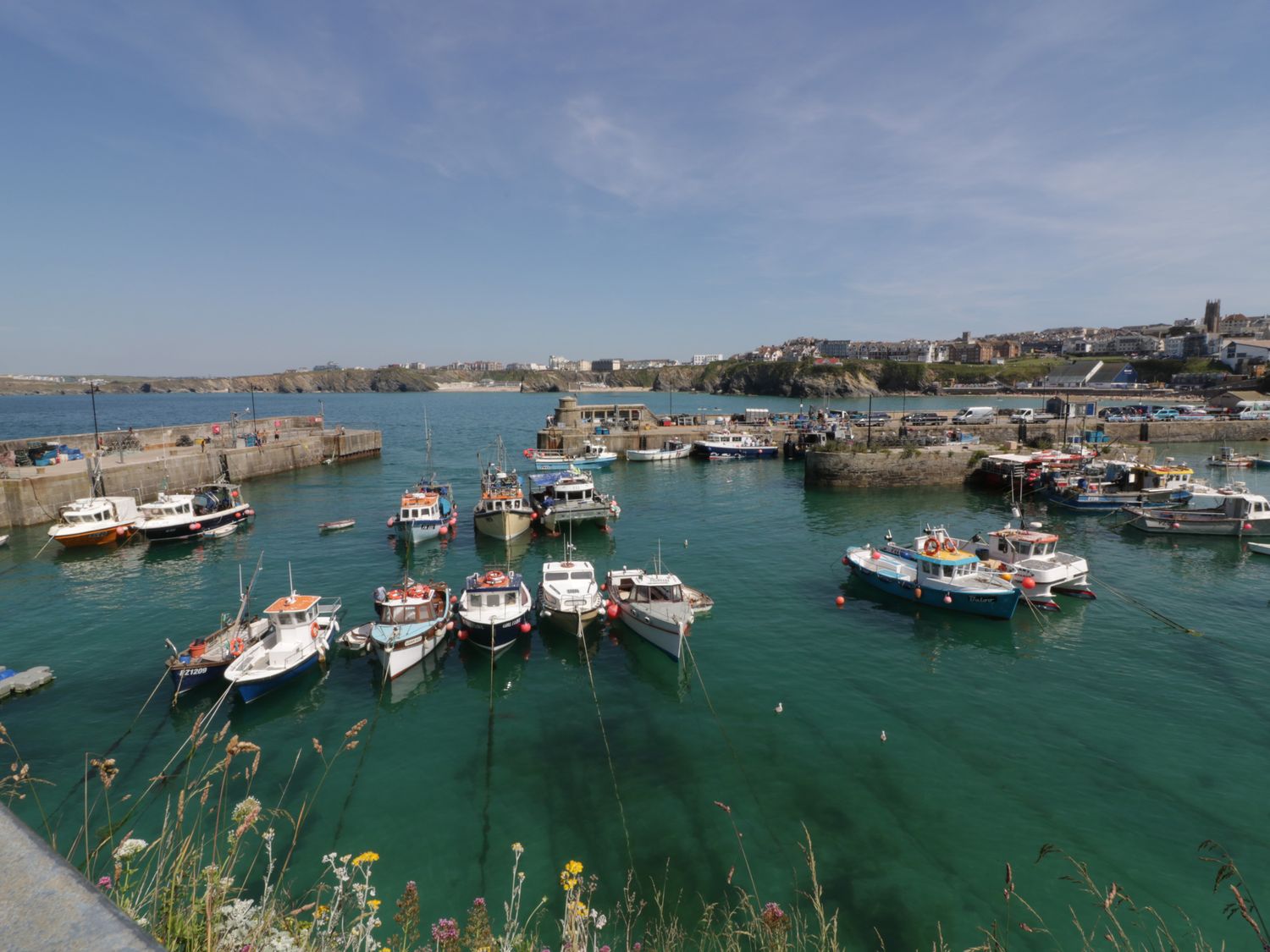 A harbor with boats docked in the water and a town in the background at Dolphin Villa in Newquay