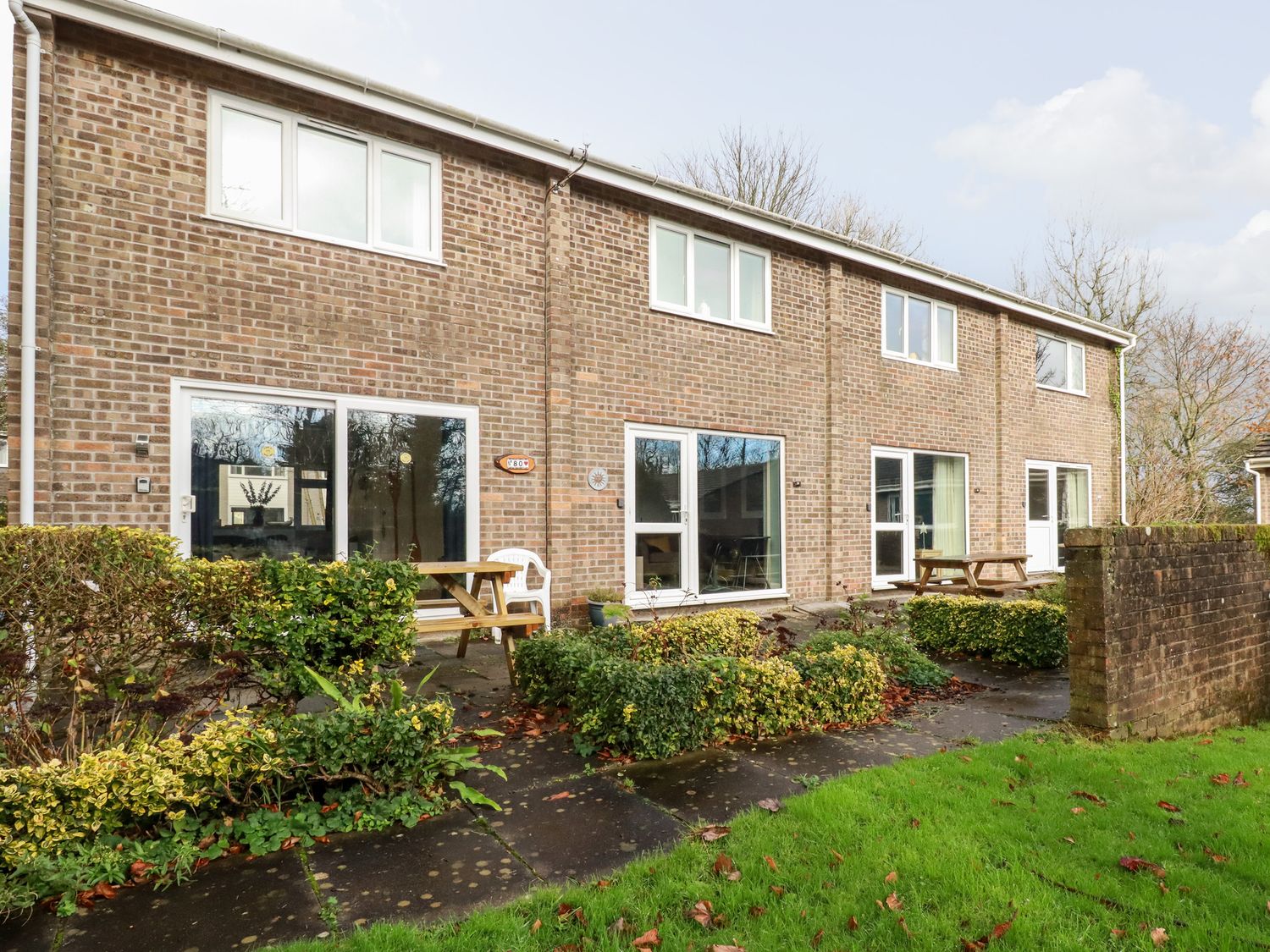 A brick apartment building with patios and picnic tables in a garden at Dolphin Villa in Newquay