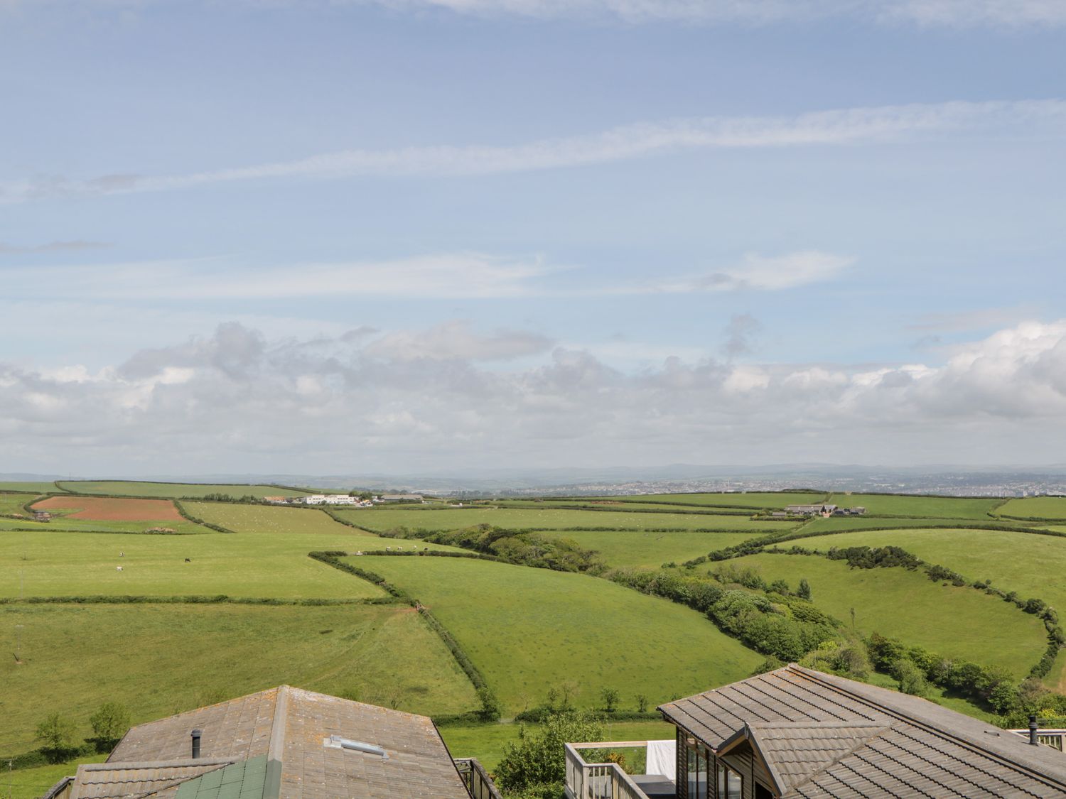 A rural landscape with green fields and farm buildings at Three Views Lodge in Whitsand Bay Fort Holiday Village